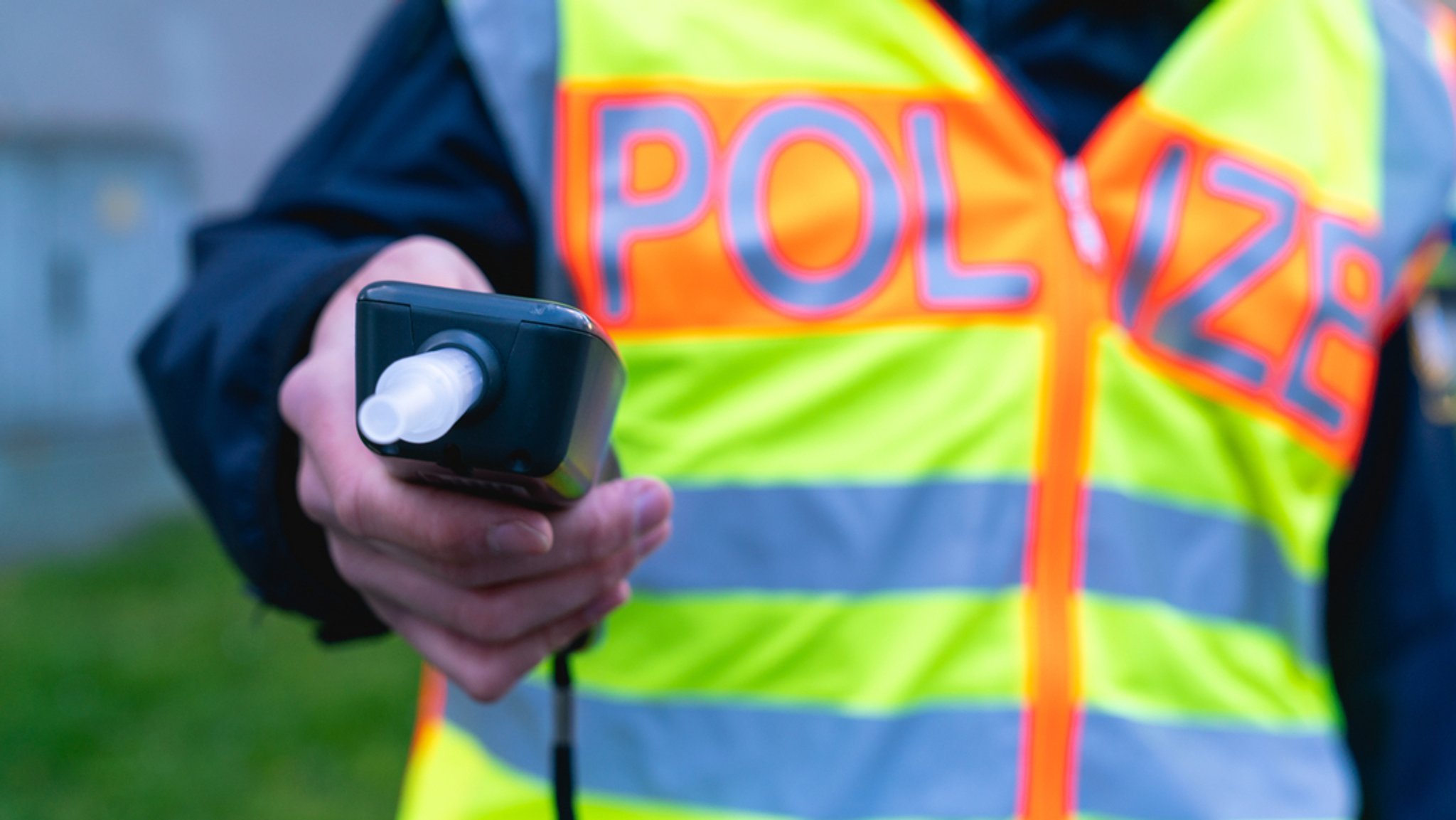 Ein Polizist hält einen Alkoholtester in der Hand.