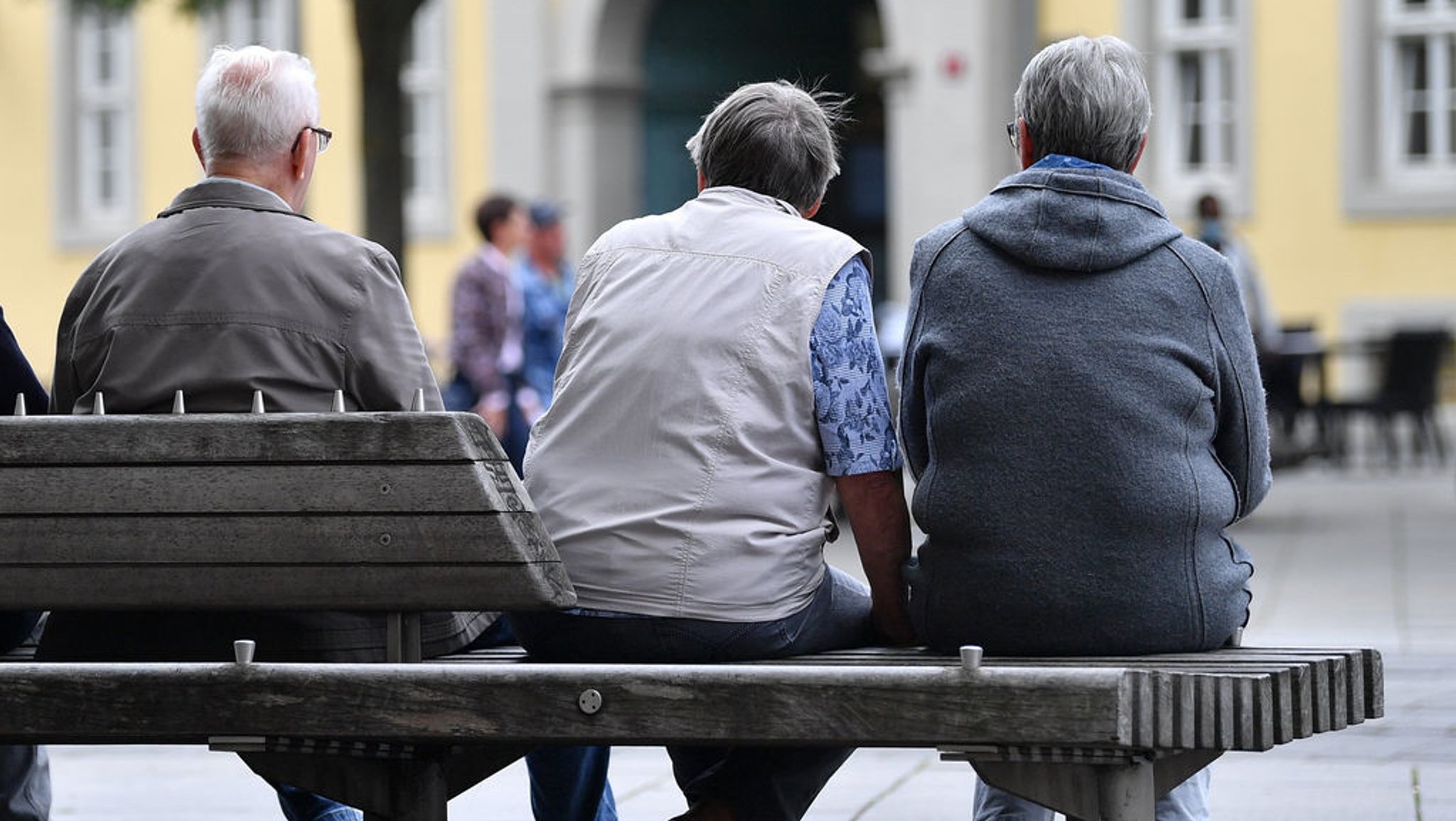 Ältere Menschen sitzen auf einer Bank.