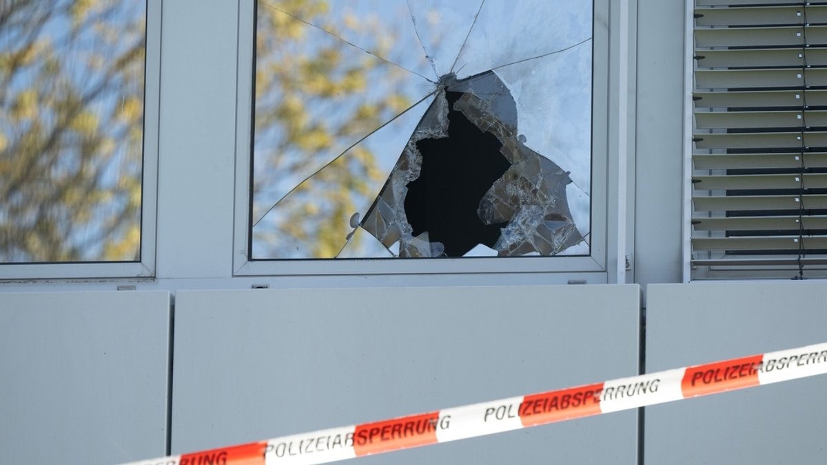Ein Absperrband der Polizei hängt vor einer zerbrochenen Fensterscheibe einer geplanten Flüchtlingsunterkunft.