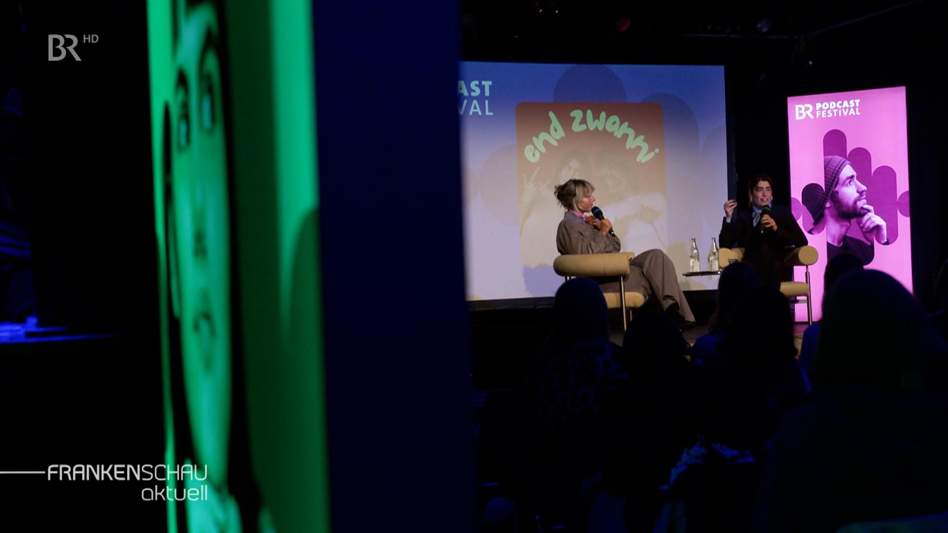 Podcaster auf der Bühne.