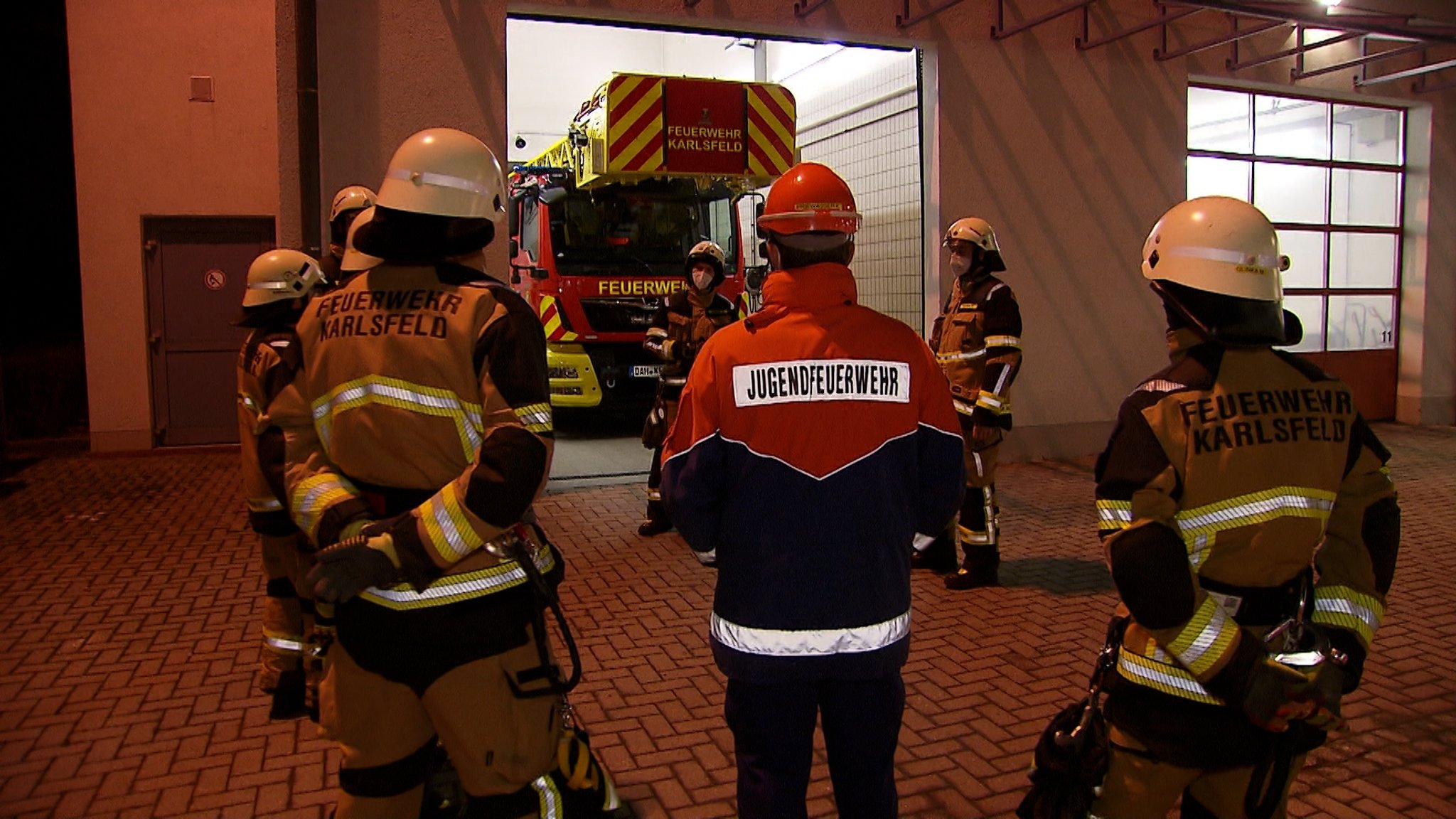 "Jugendfeuerwehr" steht auf der Jacke eines Teilnehmer, der mit anderen zusammen vor dem Feuerwehrhaus in Karlsfeld steht