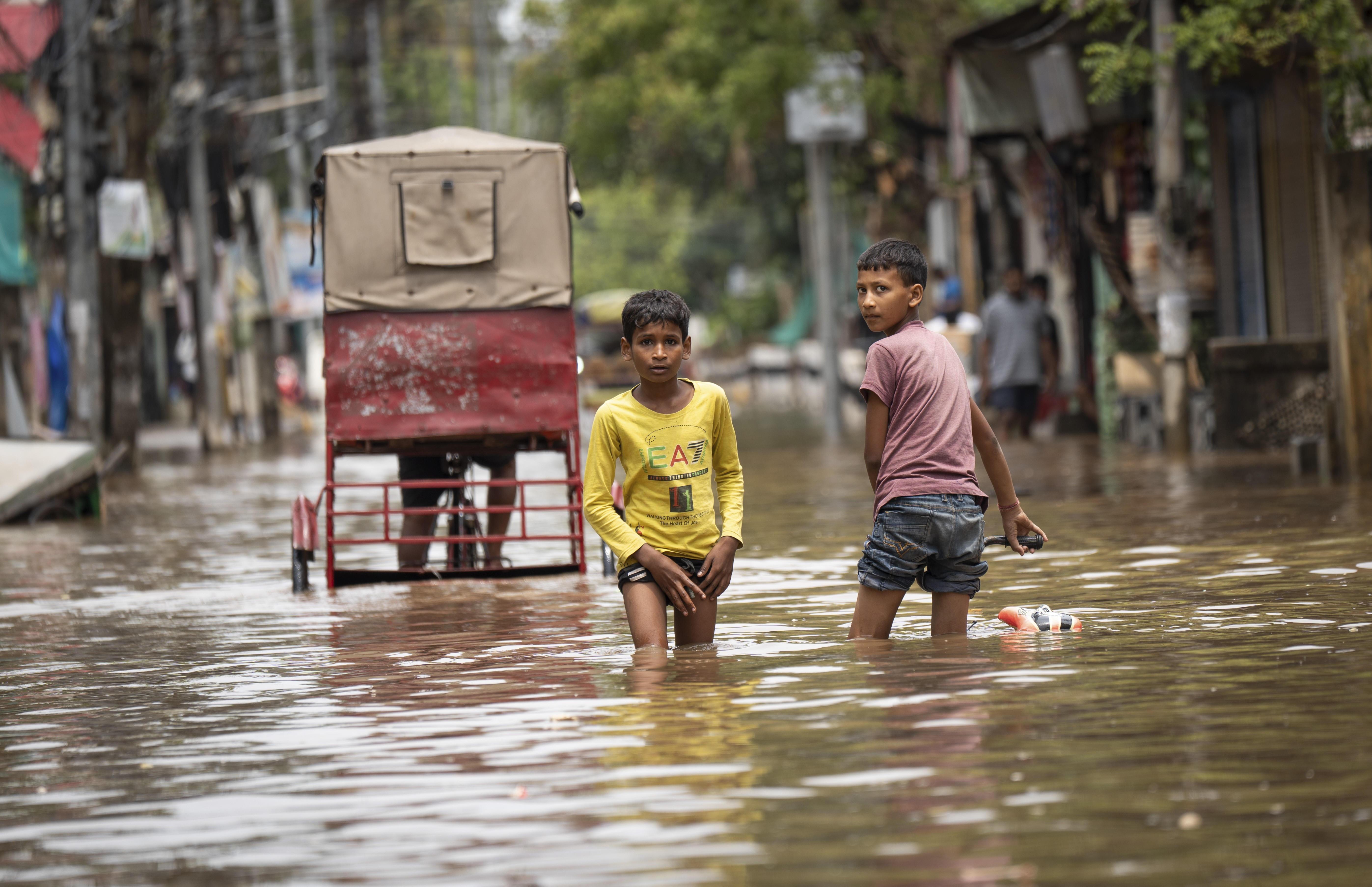 ARCHIV (28.04.2025): Kinder waten durch eine überschwemmte Straße nach schweren Regenfällen in Guwahati, Indien, am 28. April 2025, Asien