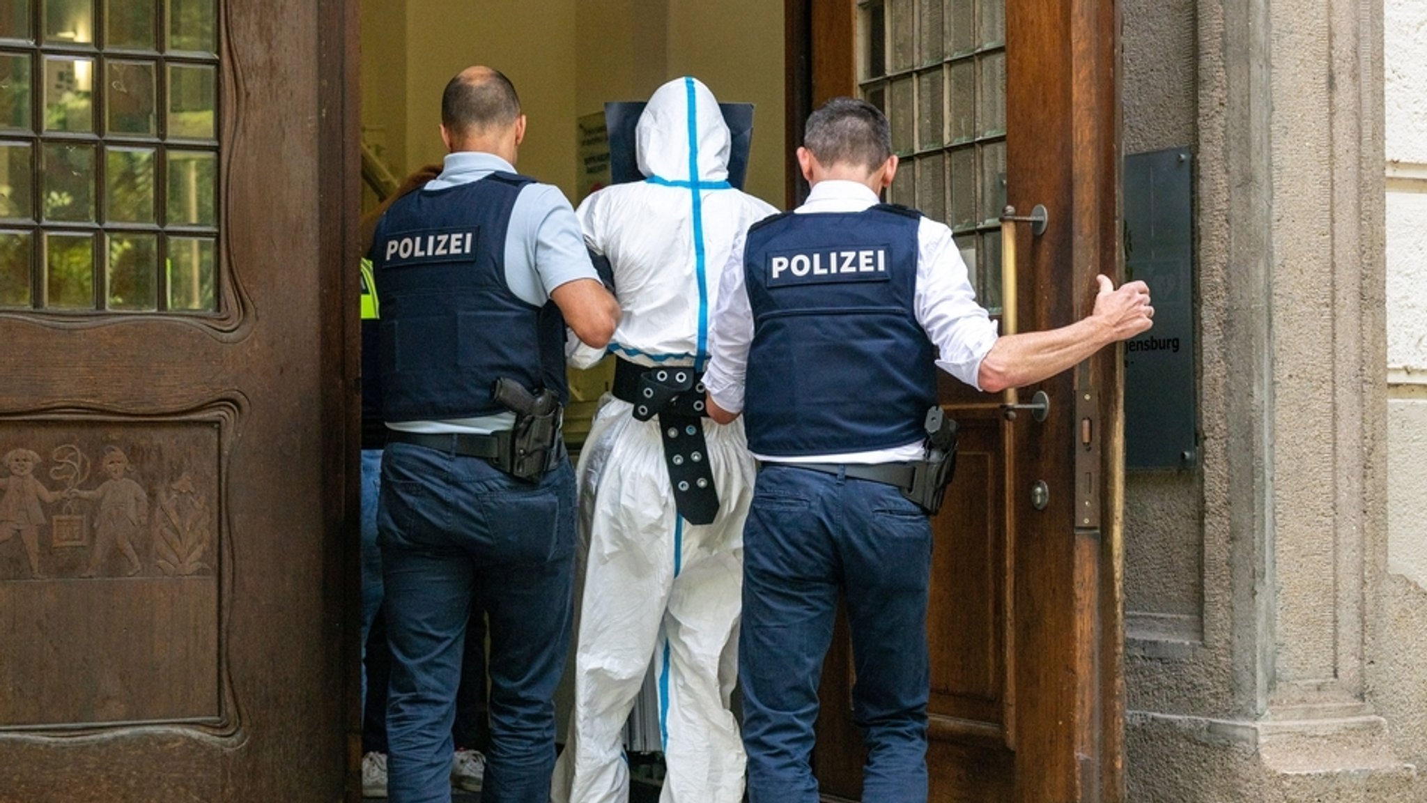 Der Tatverdächtige und Polizisten am Eingang zum Justizgebäude