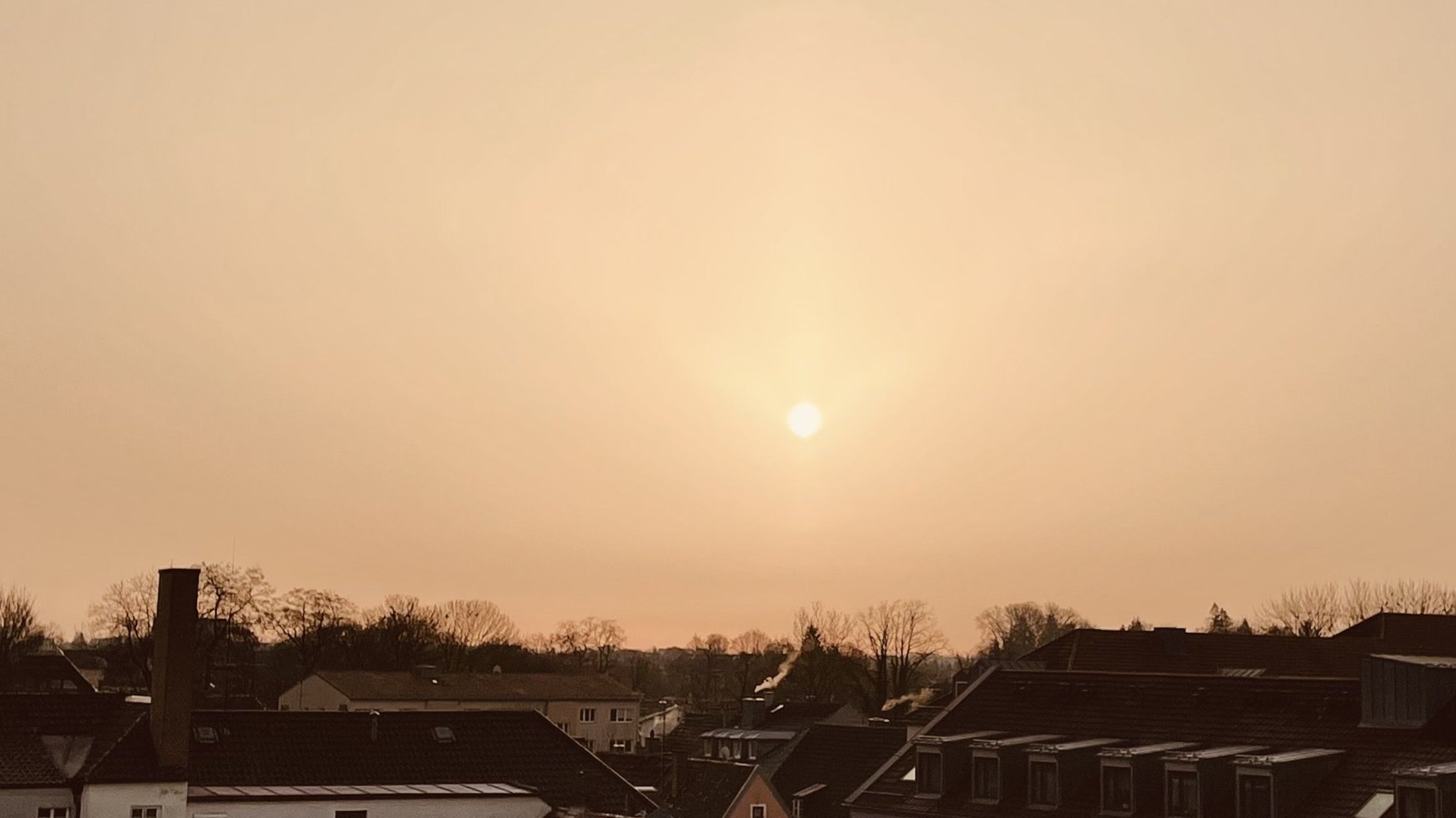 Saharasand liegt in der Luft und dimmt die Sonne, als sie am 23. Februar über Erding aufgeht