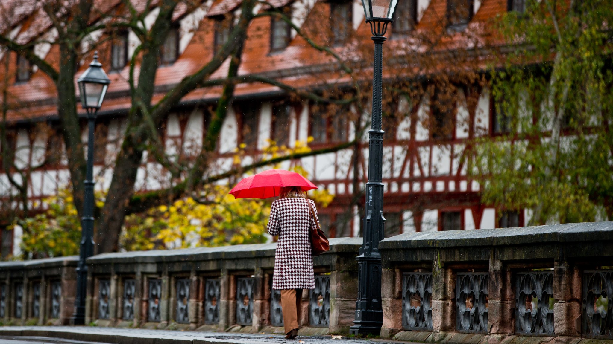 Eine Frau geht bei Regenwetter in der Altstadt von Nürnberg über die Maxbrücke. 