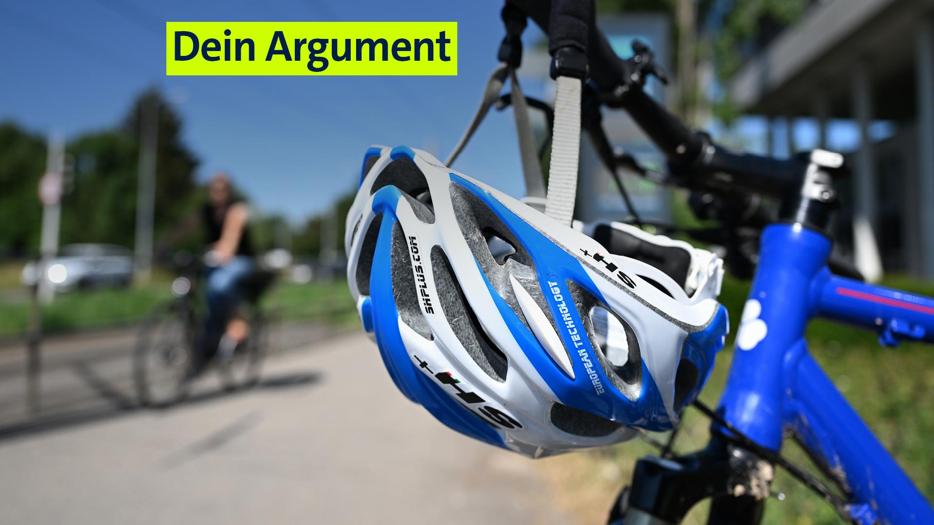 Ein Helm hängt an einem Lenker an einem Fahrrad. Im Hintergrund ist verschwommen eine Fahrradfahrerin zu sehen, die keinen Helm trägt.