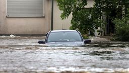 Ein Auto steht im Hochwasser der Mindel in einem Wohngebiet.  | Bild:dpa-Bildfunk/Karl-Josef Hildenbrand