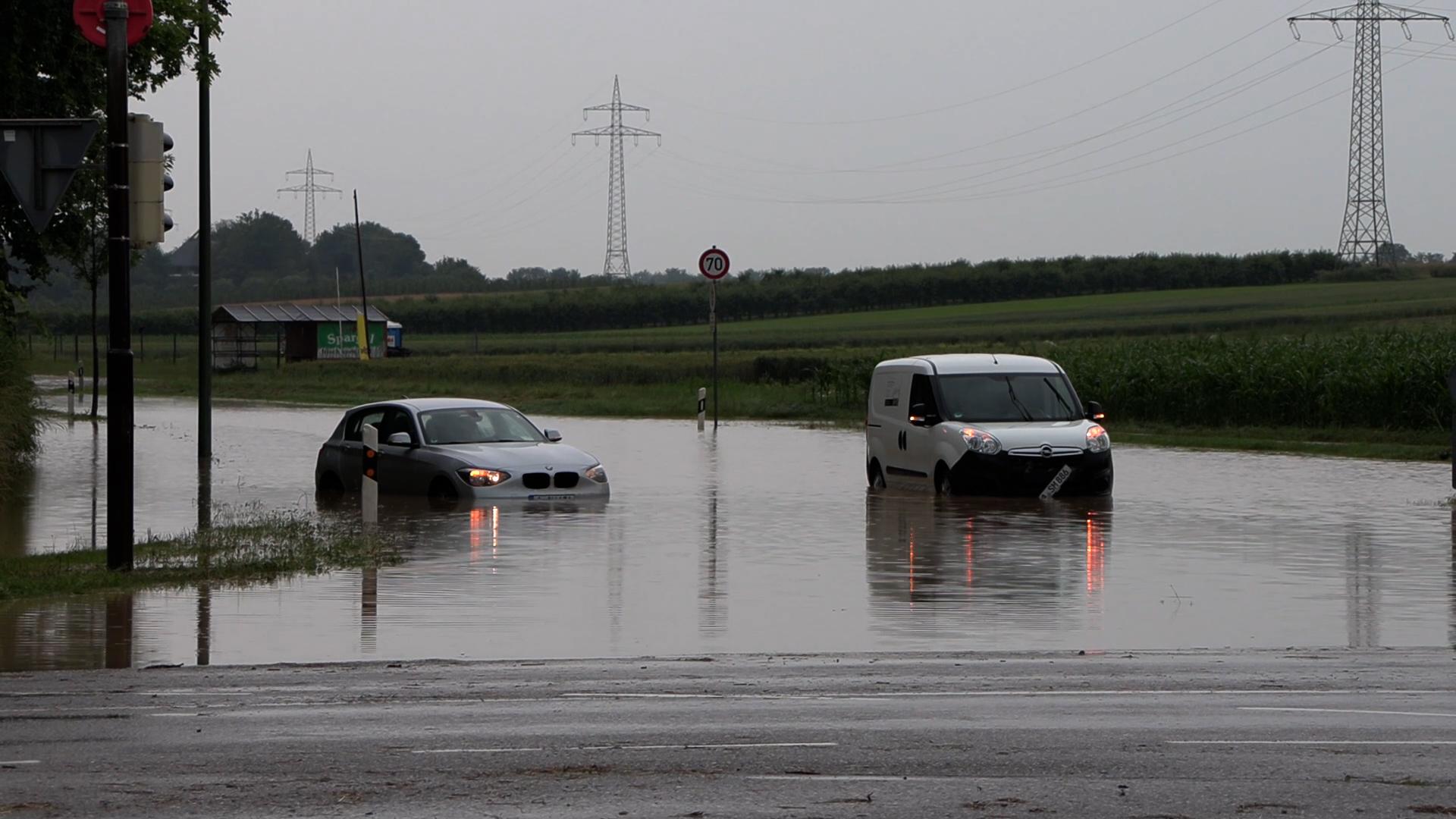 Autos stehen auf einer überfluteten Straße.