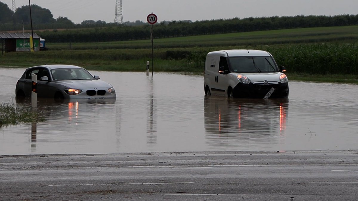 Autos stehen auf einer überfluteten Straße.