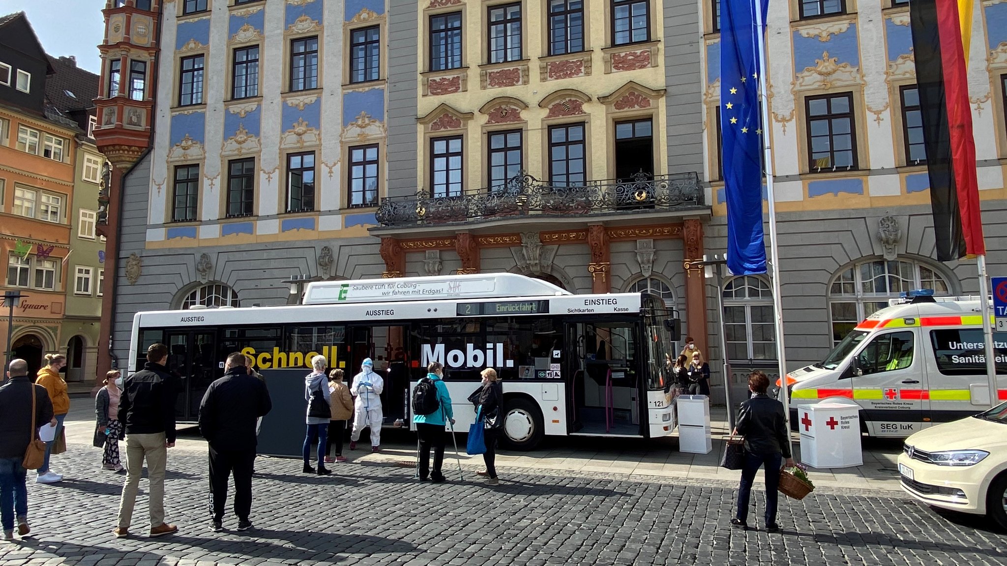 Der Testbus steht vor dem Coburger Rathaus, davor hat sich eine Menschenschlange gebildet.