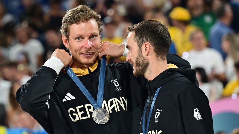 Die Beachvolleyballer Nils Ehlers (l) und Clemens Wickler jubeln mit der Silbermedaille bei der Siegerehrung. | Bild: picture alliance/dpa | Sina Schuldt Die Beachvolleyballer Nils Ehlers (l) und Clemens Wickler jubeln mit der Silbermedaille bei der Siegerehrung.
