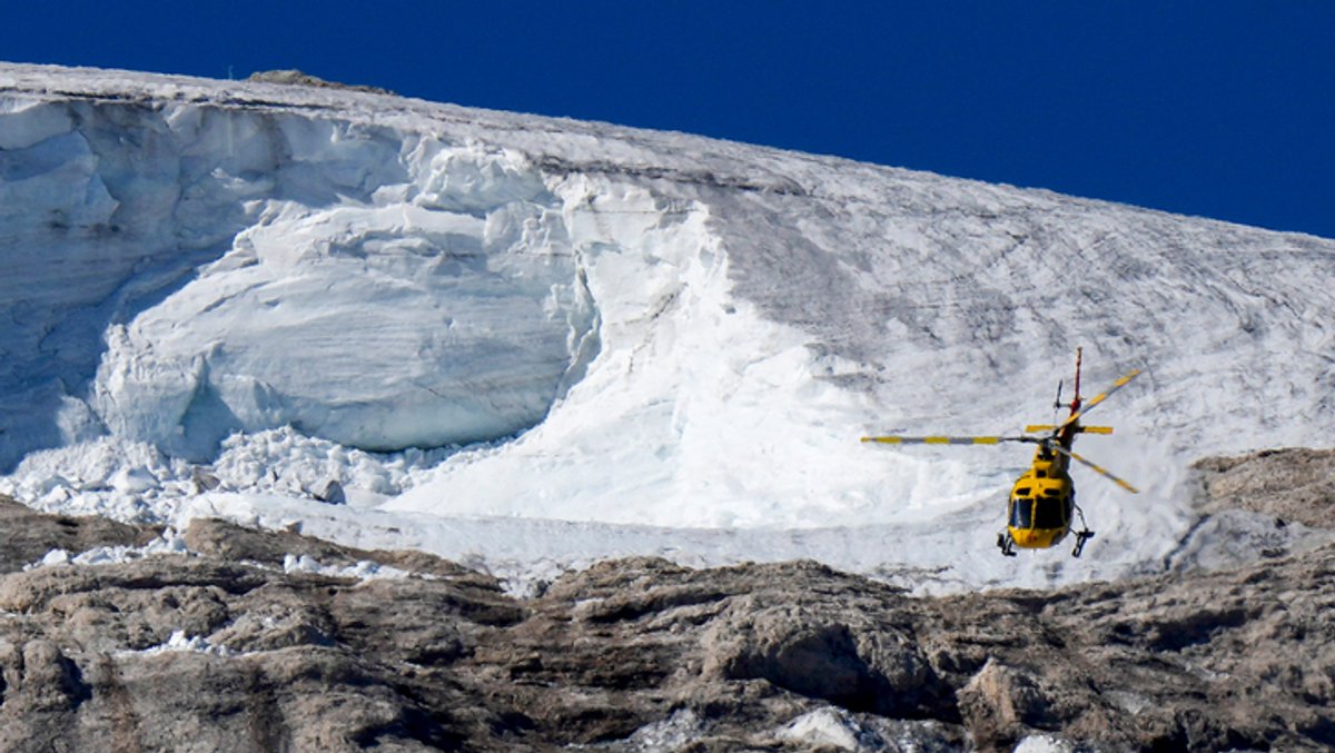 Ein Rettungshubschrauber fliegt über den Punta-Rocca-Gletscher in den italienischen Alpen. Nach dem massiven Gletscherbruch und einer Lawine geht in den Dolomiten die Suche nach weiteren Toten unter erschwerten Bedingungen weiter.