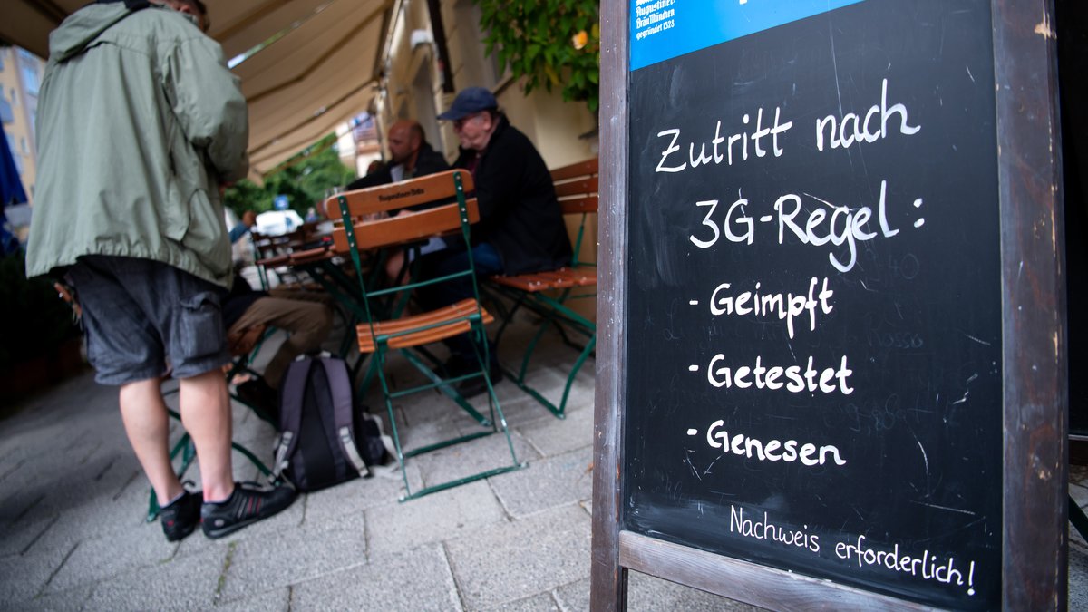 Eine Tafel mit der Aufschrift "Zutritt nach 3G-Regel: Geimpft, Getestet, Genesen" steht vor einem Wirtshaus.