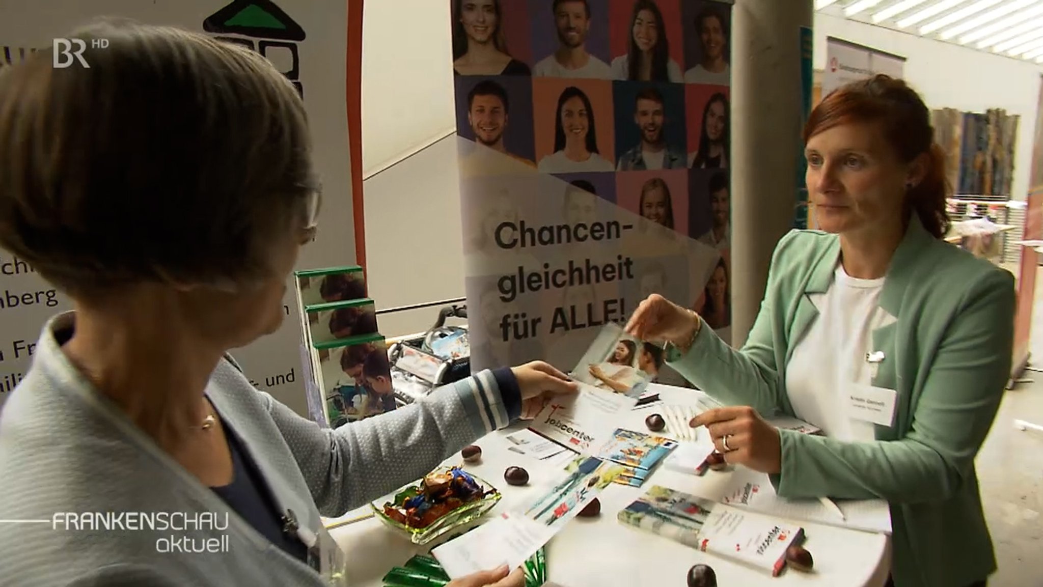 Zwei Frauen an einem Stehtisch mit Informationsmaterial.