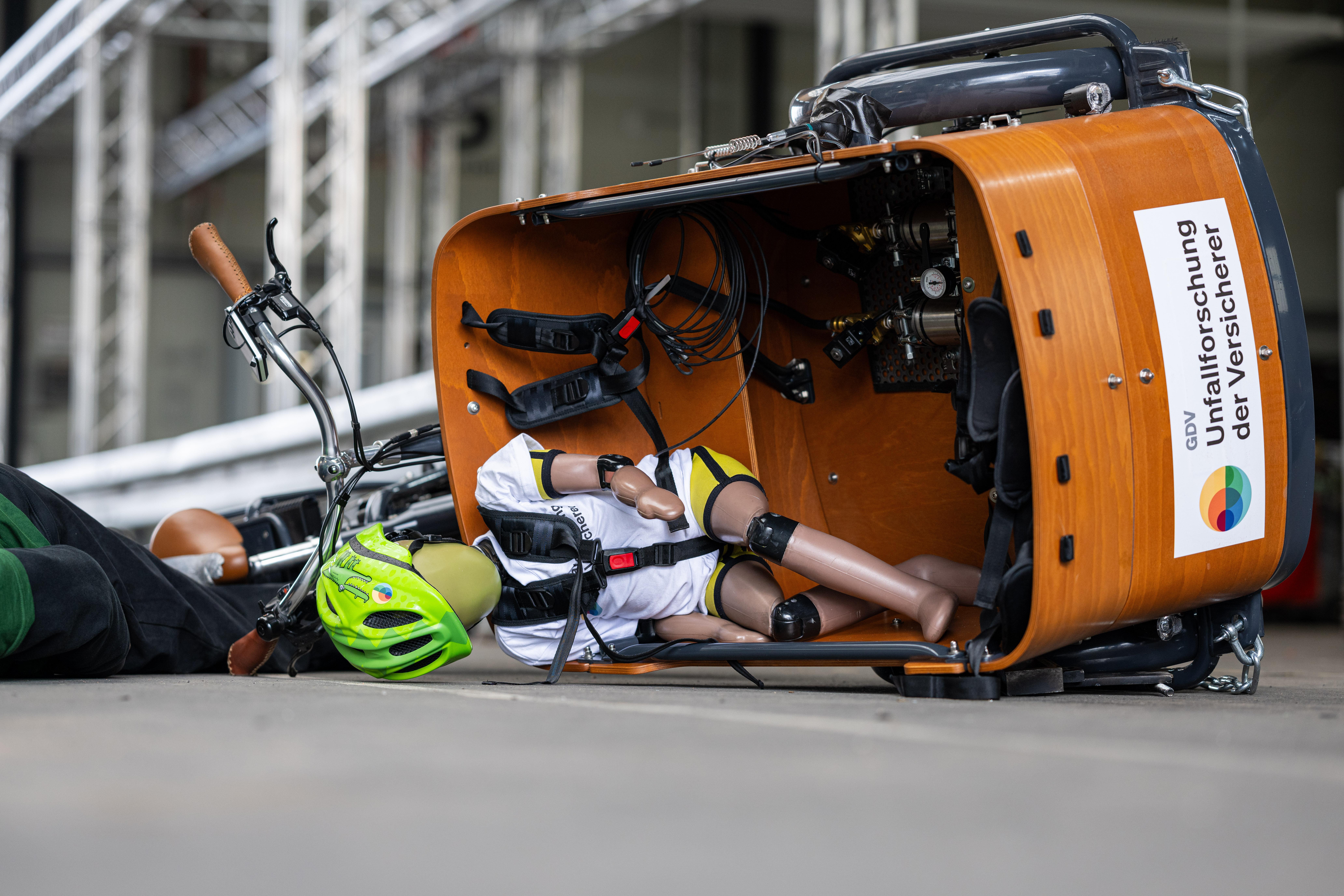 Bei einem Crashtest mit Dummys liegt ein Lastenfahrrad nach einem Bremsmanöver auf der Seite.