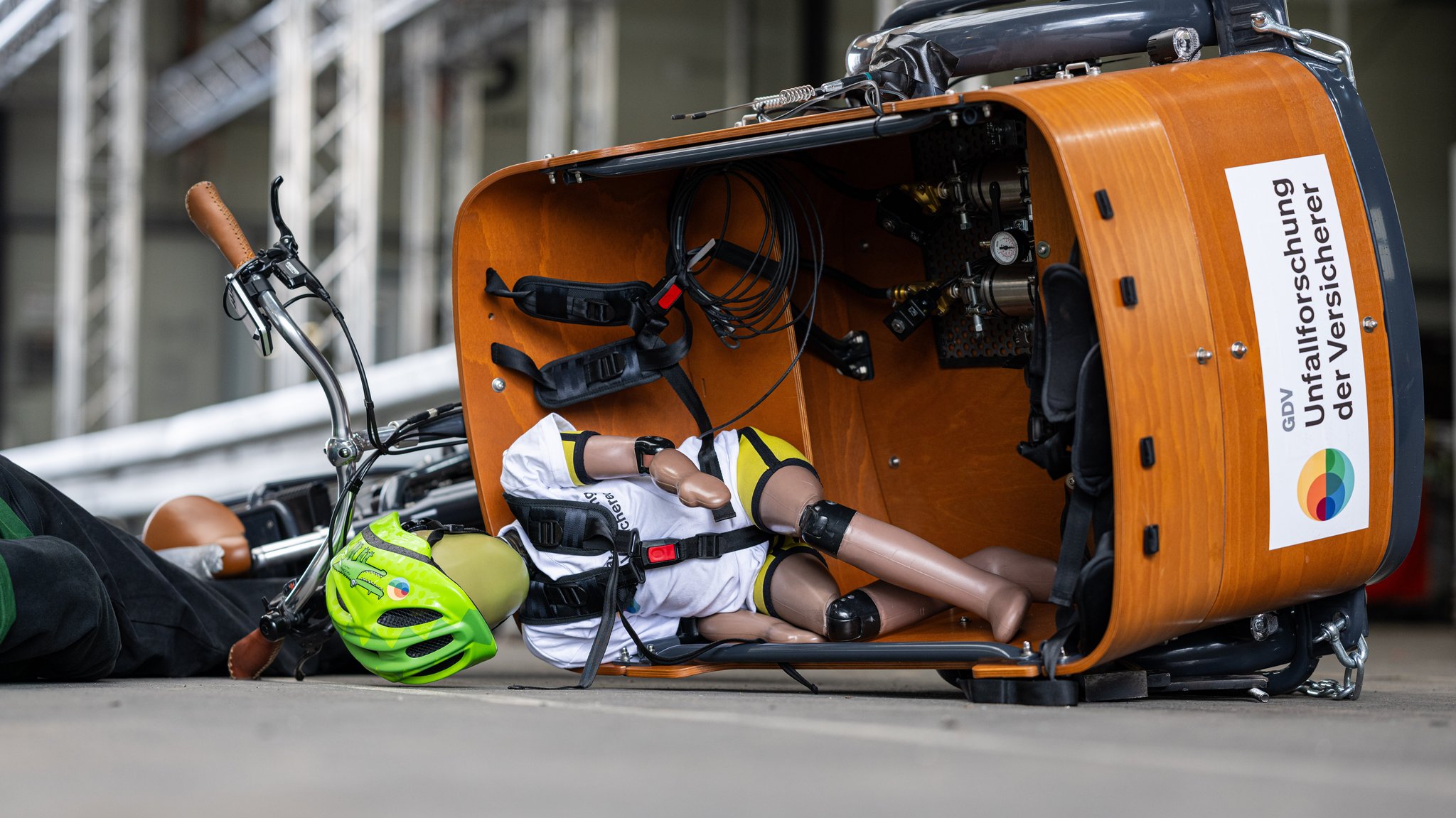 Bei einem Crashtest mit Dummys liegt ein Lastenfahrrad nach einem Bremsmanöver auf der Seite.