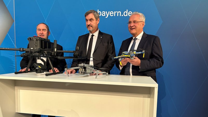 Ministerpräsident Markus Söder, Wirtschaftsminister Hubert Aiwanger (l.) und Innenminister Joachim Hermann (r.) bei der Drohnen-Pressekonferenz. | Bild: Bayerischer Rundfunk 2025 Ministerpräsident Markus Söder, Wirtschaftsminister Hubert Aiwanger (l.) und Innenminister Joachim Hermann (r.) bei der Drohnen-Pressekonferenz.
