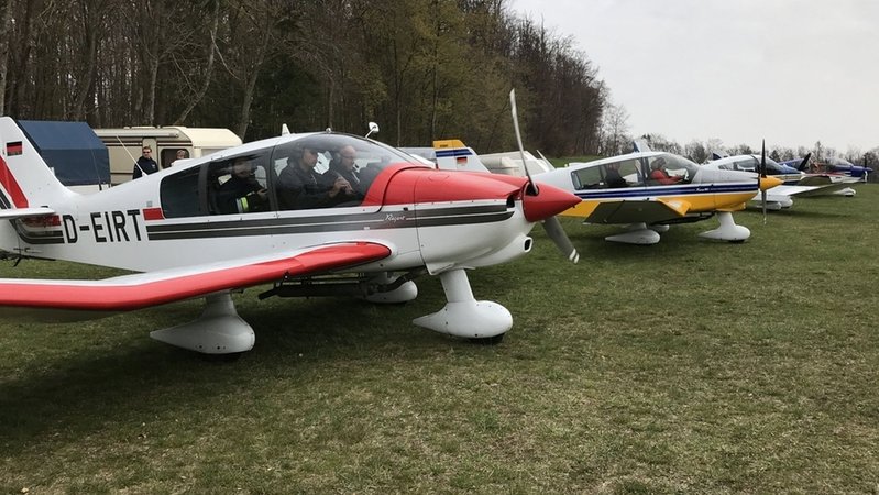 Vor einem Wald stehen auf einer Wiese Propellerflugzeuge. | Bild: BR/Andrea Kwasniok Vor einem Wald stehen auf einer Wiese Propellerflugzeuge.