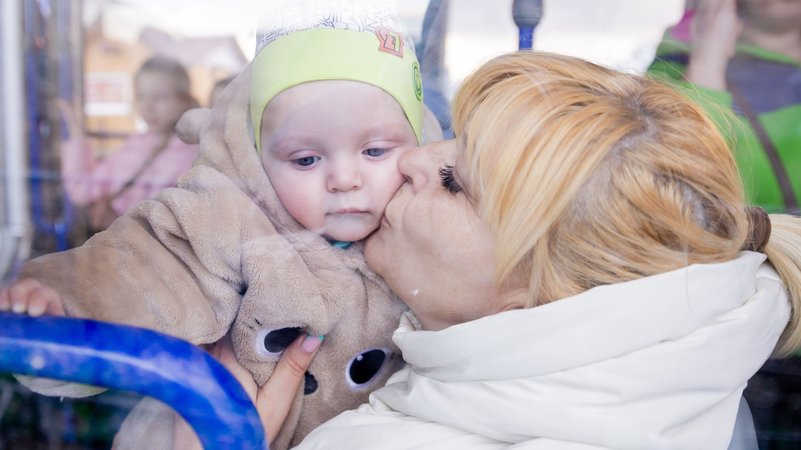 Eine Großmutter im Bus küsst am Grenzübergang hinter der ukrainischen Grenze ihren kleinen Enkel.