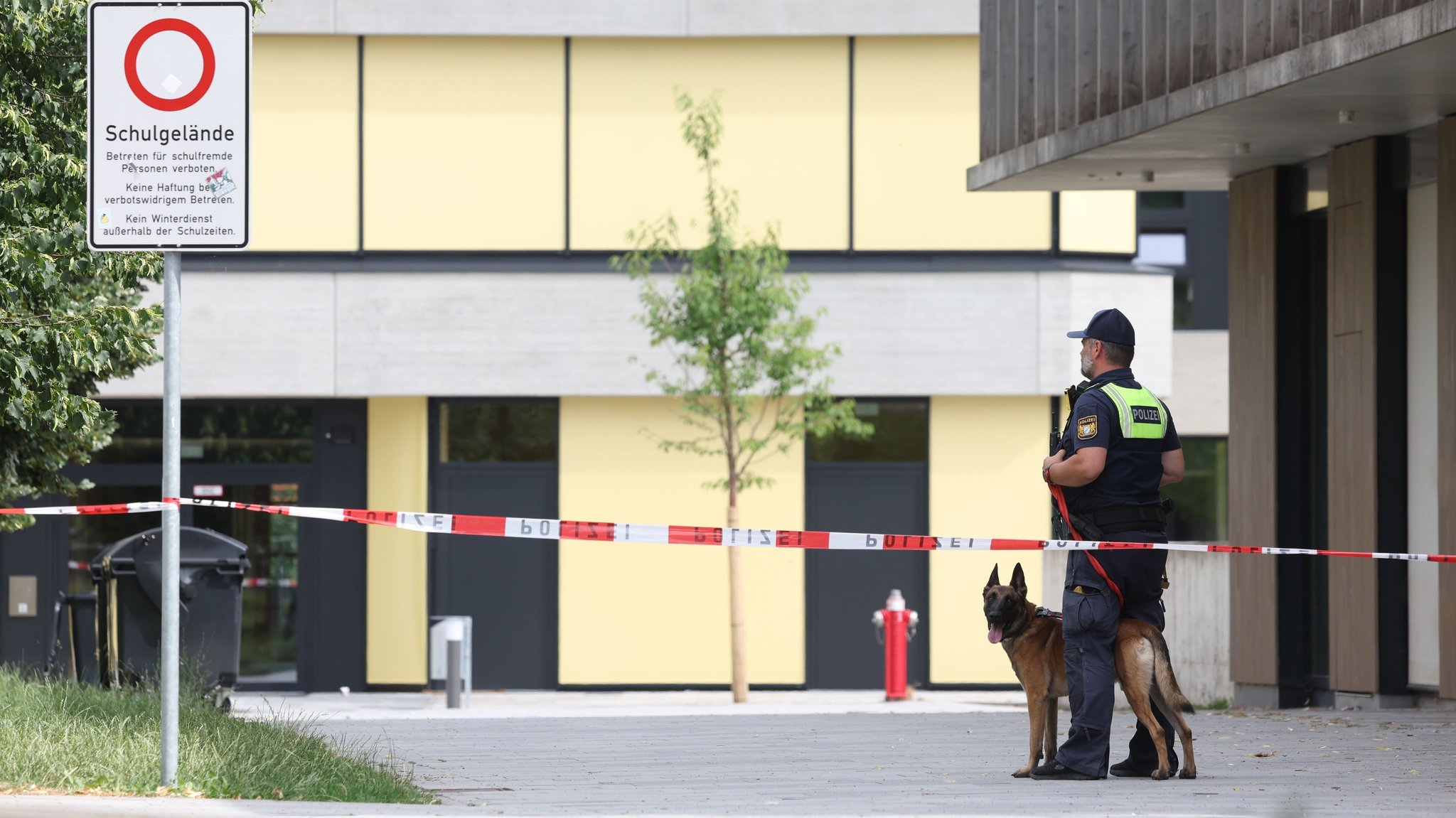 (Archivbild) Zu sehen ist ein Polizeibeamter und ein Polizeihund hinter Absperrband. Im Hintergrund ist die Schule in Schongau zu sehen. | Bild: dpa-Bildfunk/Karl-Josef Hildenbrand (Archivbild) Zu sehen ist ein Polizeibeamter und ein Polizeihund hinter Absperrband. Im Hintergrund ist die Schule in Schongau zu sehen.