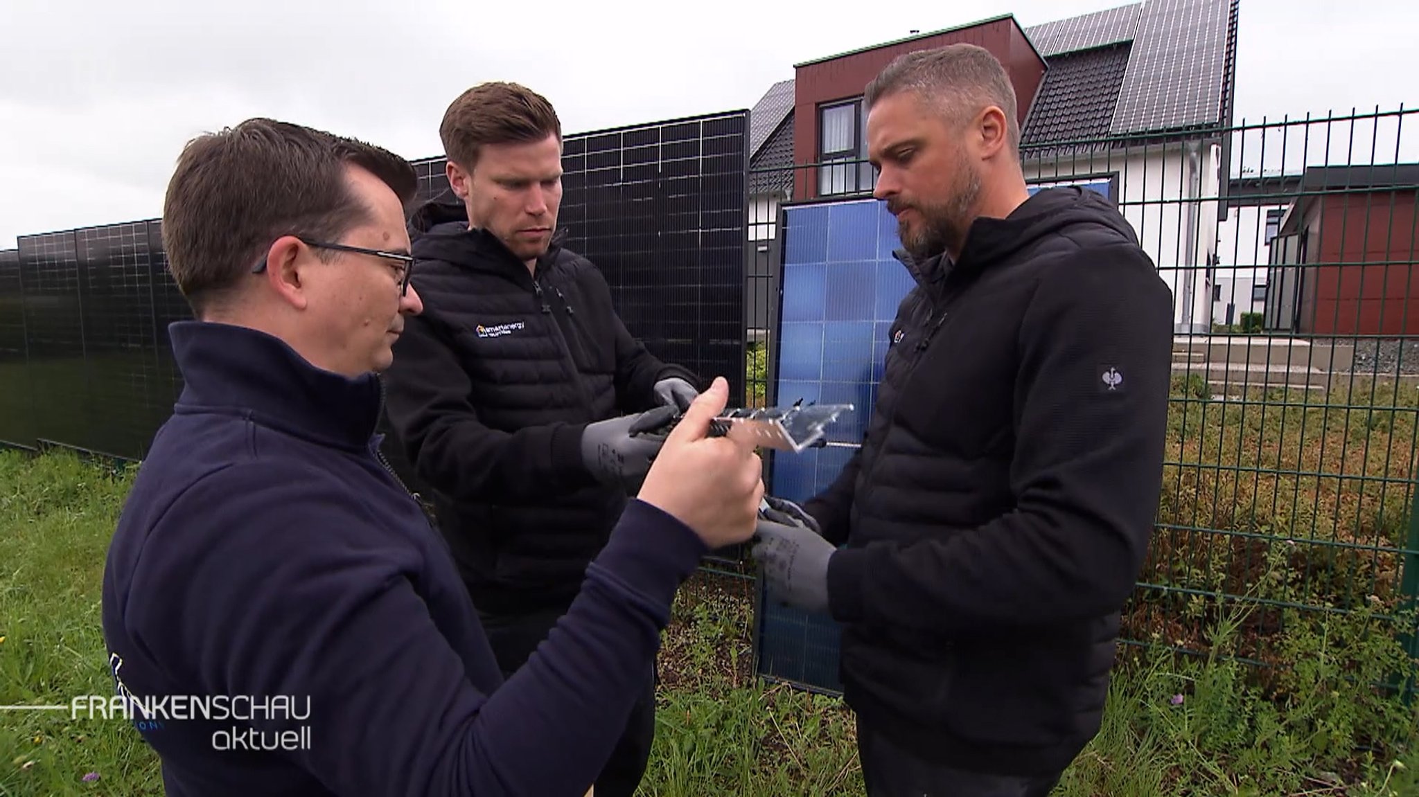 Tüftler-Team vor Solarmodulen an den Zäunen.