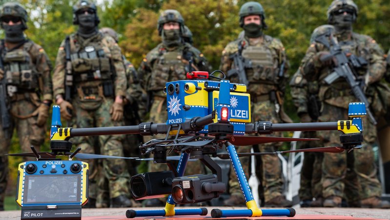 Gemeinsame Einsatzübung der Bayerischen Polizei und der Deutschen Bundeswehr RoadTEX 2025 (Übung Anschlag im Verkehrsraum). Eine Polizeidrohne steht einsatzbereit vor einer Formation von Bundeswehrsoldaten. (Aufnahmedatum: 09.10.2025) | Bild: picture alliance / CHROMORANGE | Michael Bihlmayer Gemeinsame Einsatzübung der Bayerischen Polizei und der Deutschen Bundeswehr RoadTEX 2025 (Übung Anschlag im Verkehrsraum). Eine Polizeidrohne steht einsatzbereit vor einer Formation von Bundeswehrsoldaten. (Aufnahmedatum: 09.10.2025)