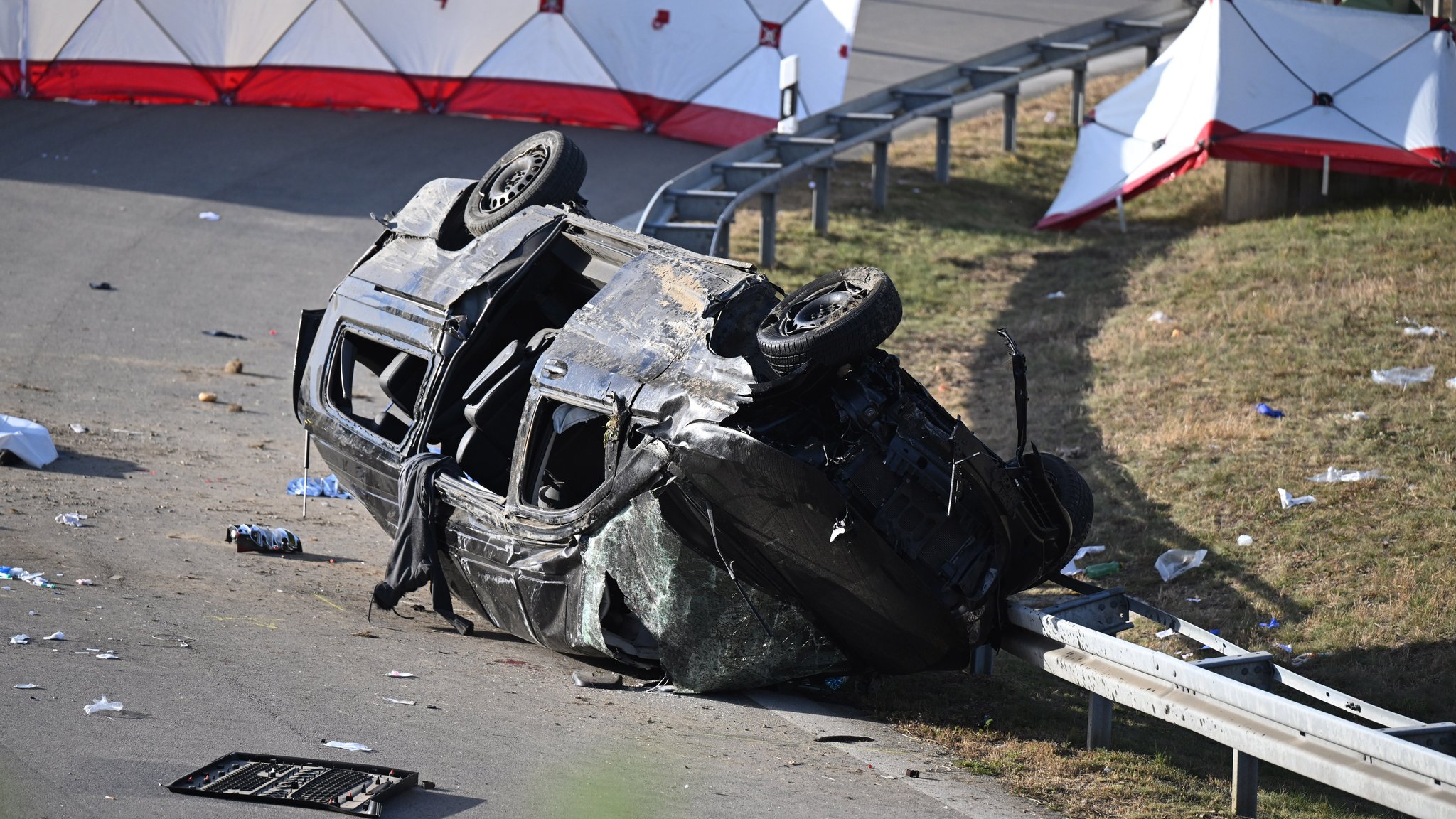 Betreuer der Polizei stehen am Rande des umgestürzten Fahrzeugs. Beim Unfall eines mutmaßlichen Schleuserfahrzeugs auf der Autobahn 94 sind sieben Menschen gestorben und mehrere schwer verletzt worden. Der mit mehr als 20 Personen völlig überfüllte Transporter war beim Versuch, einer Polizeikontrolle davonzufahren, von der Straße abgekommen .