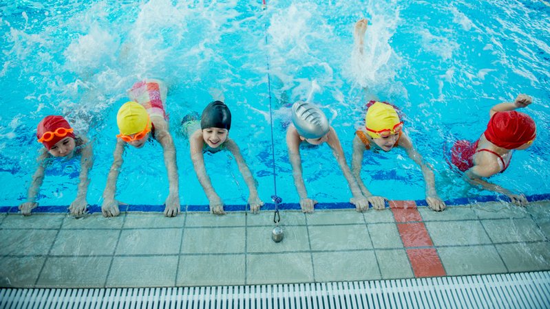 Eine Gruppe von Mädchen übt am Beckenrand eines Schwimmbeckens Schwimmen. | Bild: stock.adobe.com/FS-Stock Eine Gruppe von Mädchen übt am Beckenrand eines Schwimmbeckens Schwimmen.