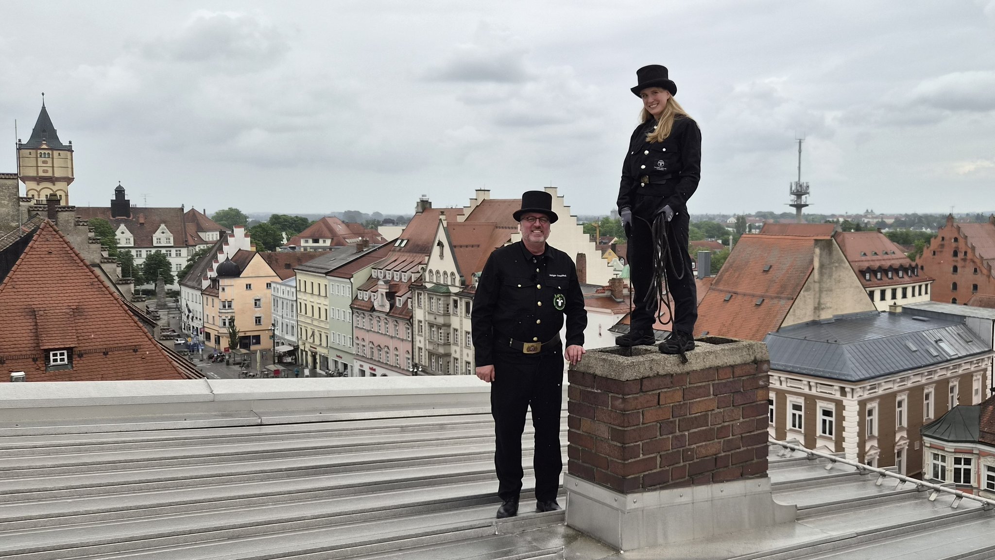 Ein Schornsteinfeger und eine Schornsteinfegerin stehen auf einem Hausdach in Straubing | Bild: BR/Christian Akber-Sade Ein Schornsteinfeger und eine Schornsteinfegerin stehen auf einem Hausdach in Straubing