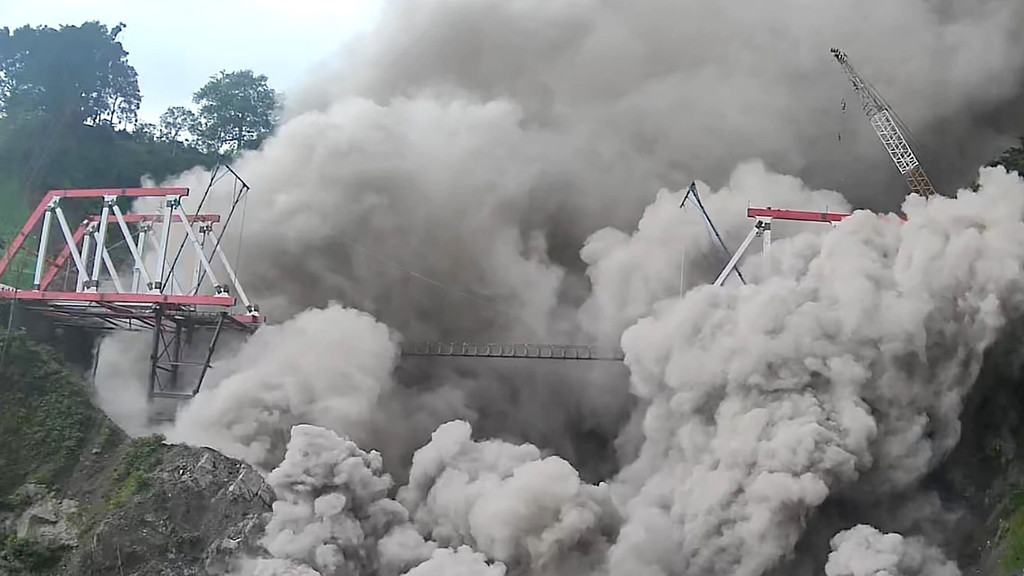 Eine große Staub- und Geröllwolke reißt eine Brücke in Indonesien weg.