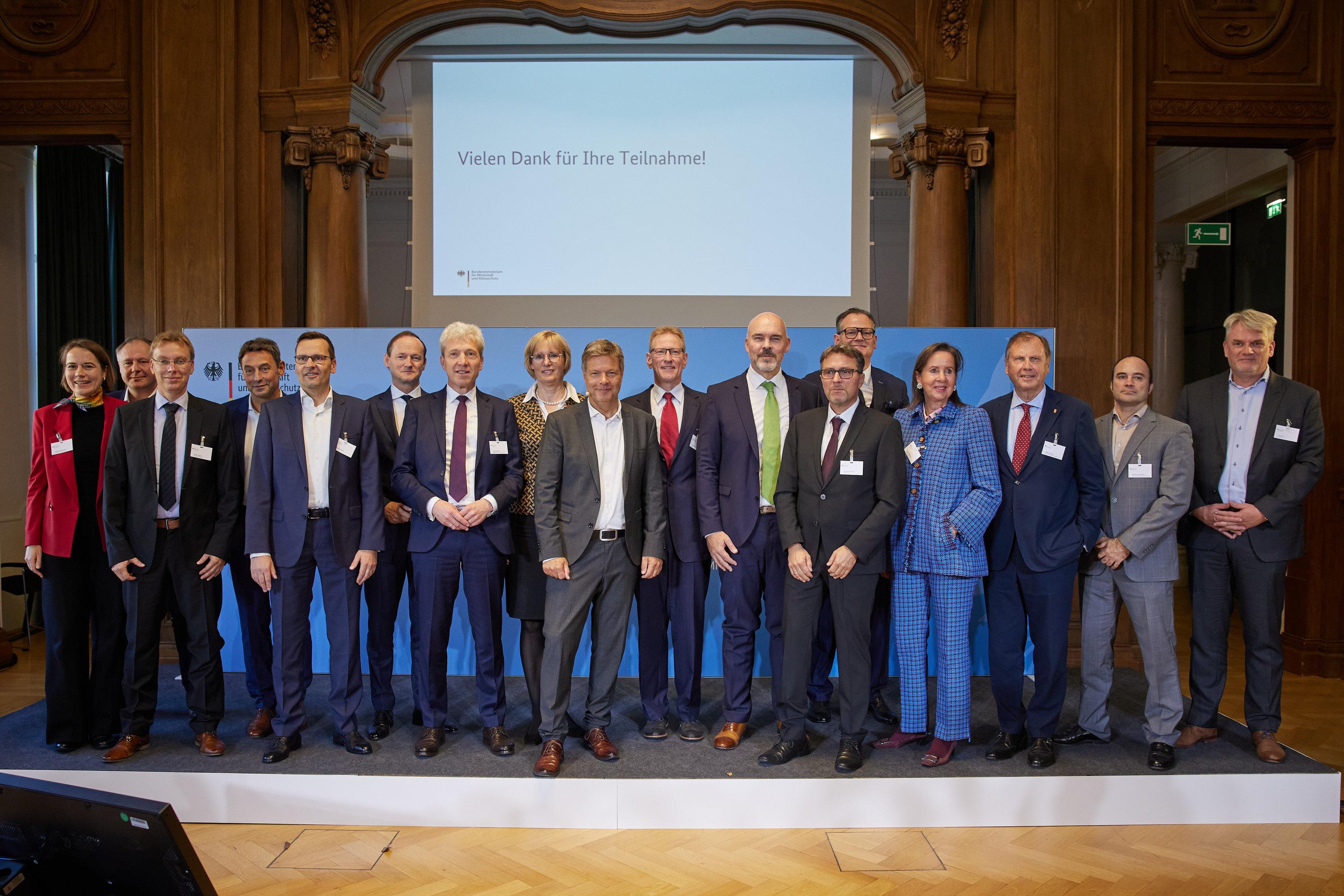 Robert Habeck steht gemeinsam mit Unternehmensvertretern für ein Pressefoto auf einer Bühne.