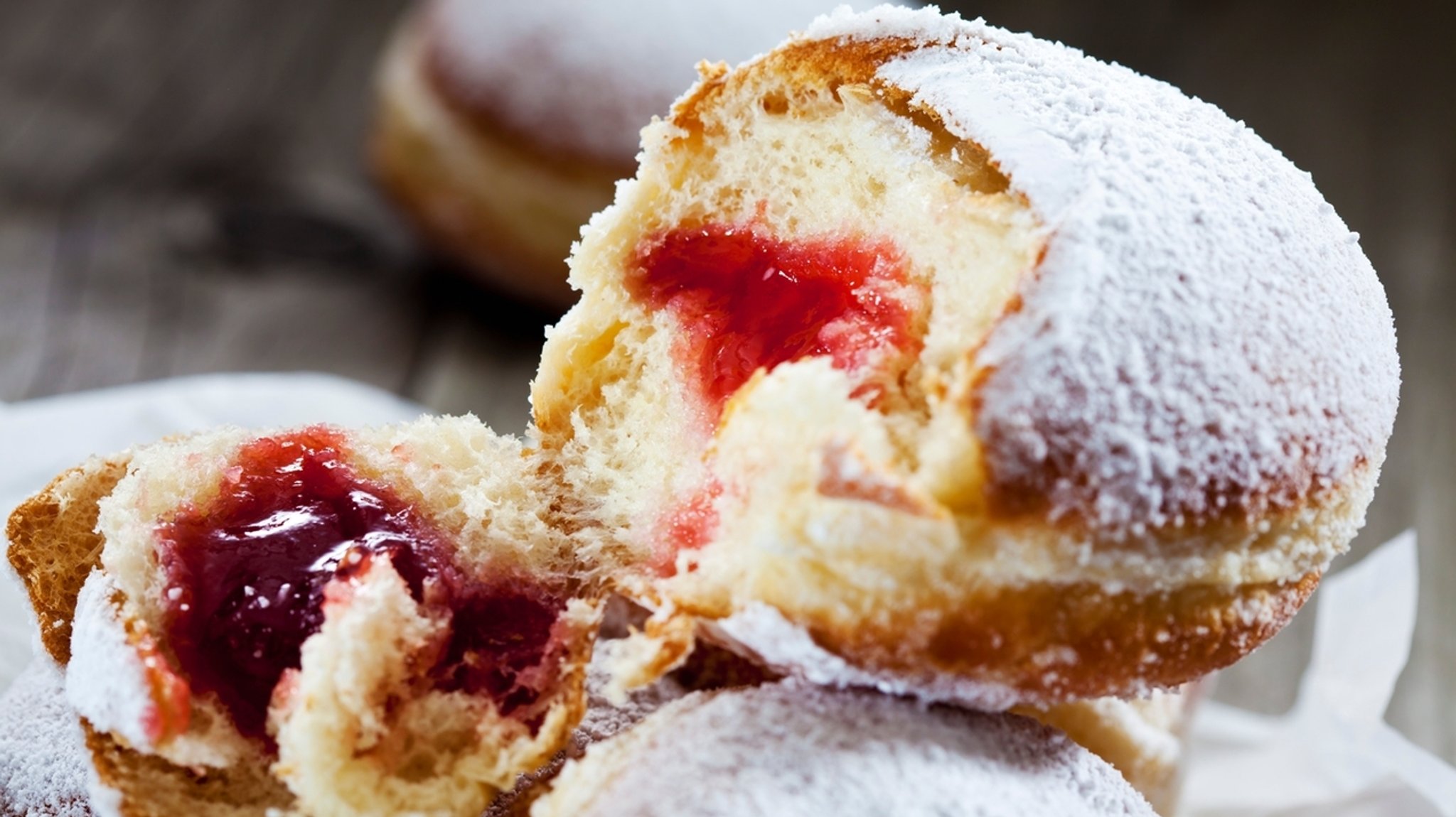 Ein aufgebrochener Krapfen zeigt sein marmeladiges Innenleben.
