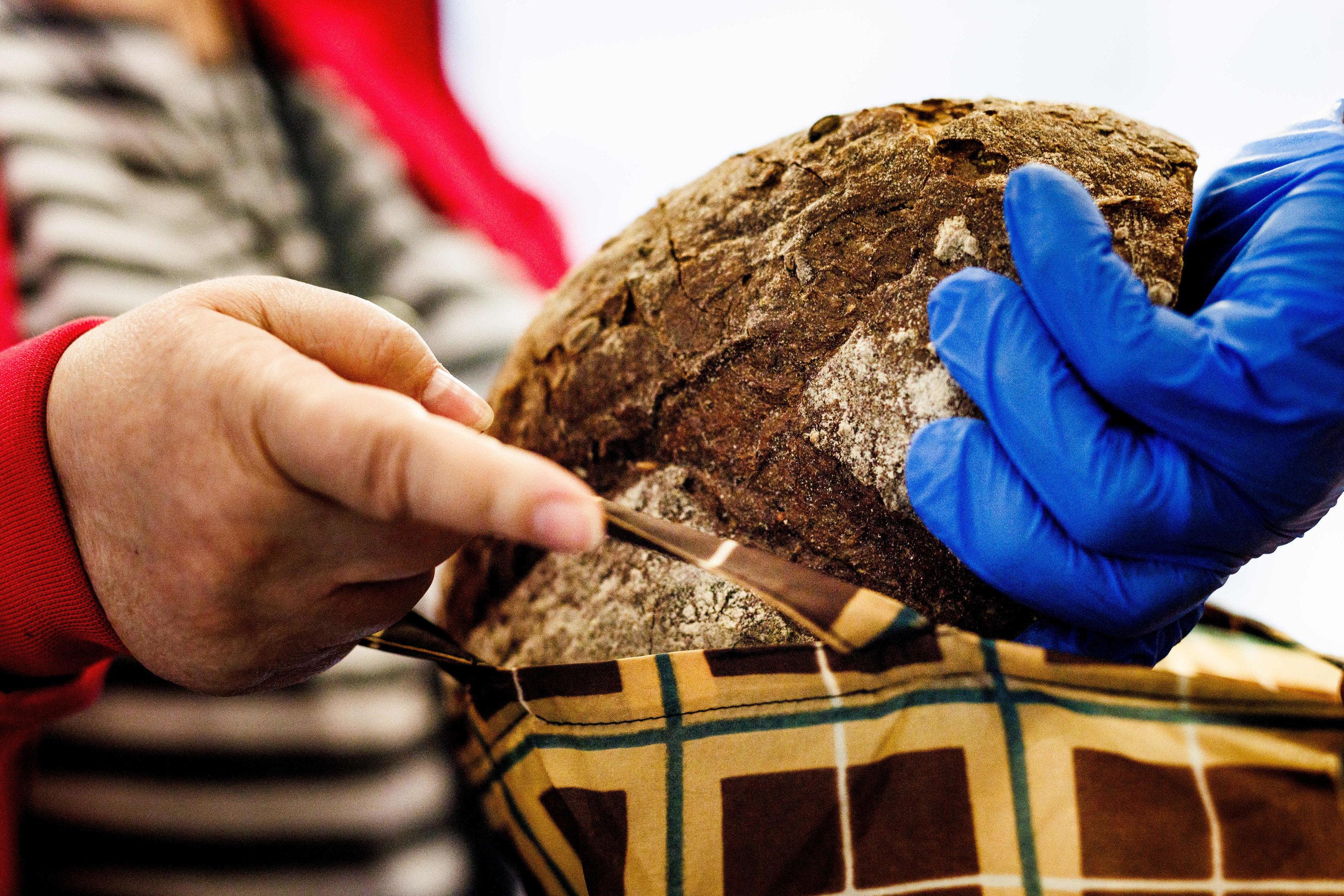 Ein Mitarbeiter der Tafel legt ein Brot in die Tasche einer Frau.