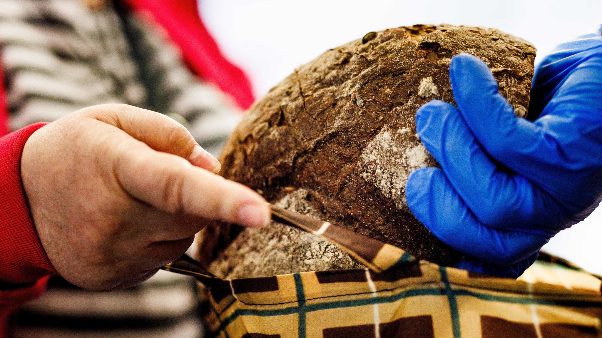 Ein Mitarbeiter der Tafel legt ein Brot in die Tasche einer Frau.