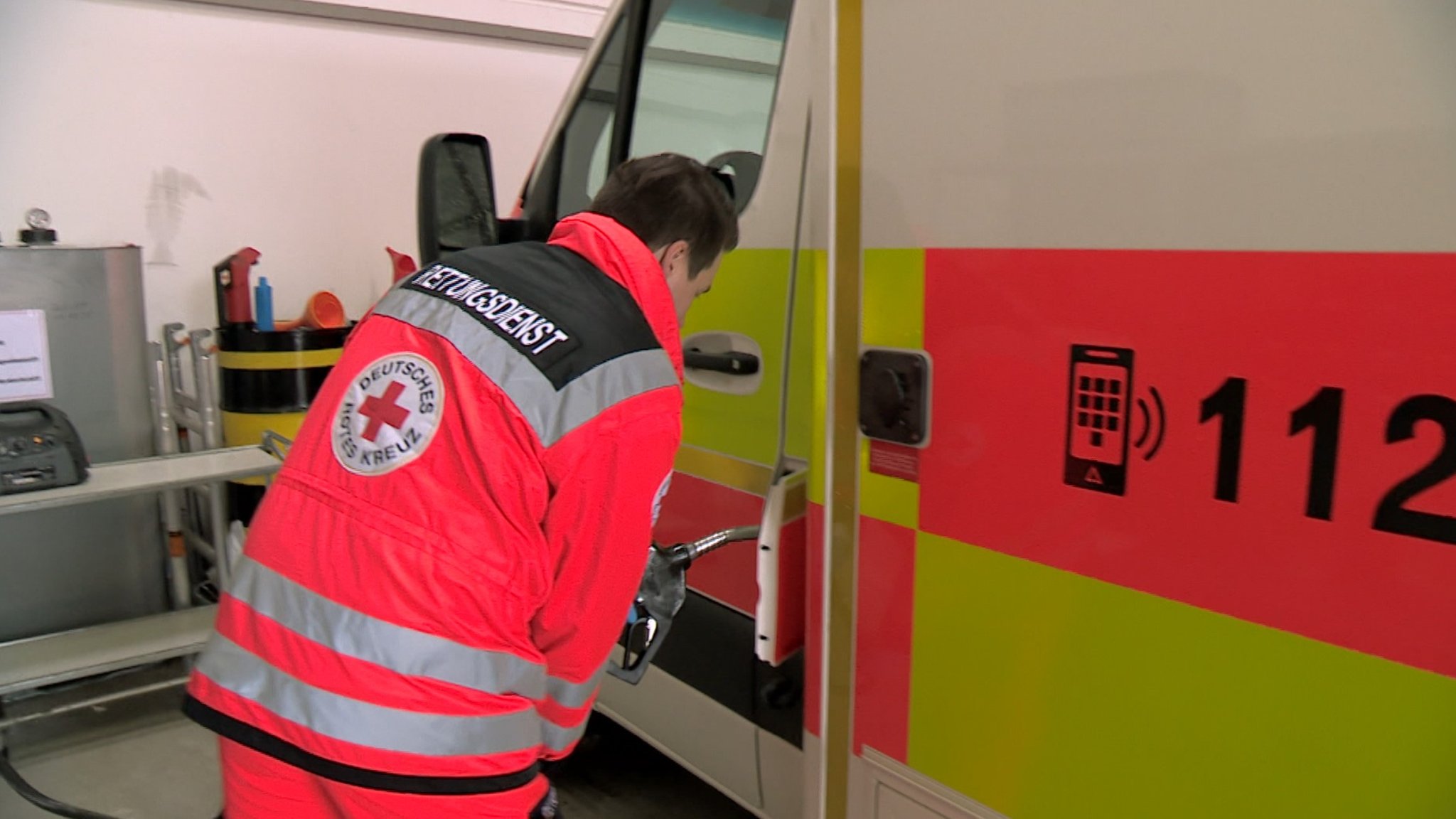 Ein Sanitäter steht vor einem Einsatzwagen mit der Notrufnummer 112. | Bild: BR Ein Sanitäter steht vor einem Einsatzwagen mit der Notrufnummer 112.