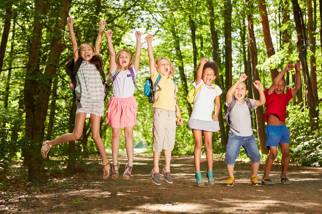 Sechs Kindern auf einem Waldweg die in die Luft springen