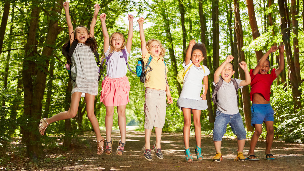 Sechs Kindern auf einem Waldweg die in die Luft springen