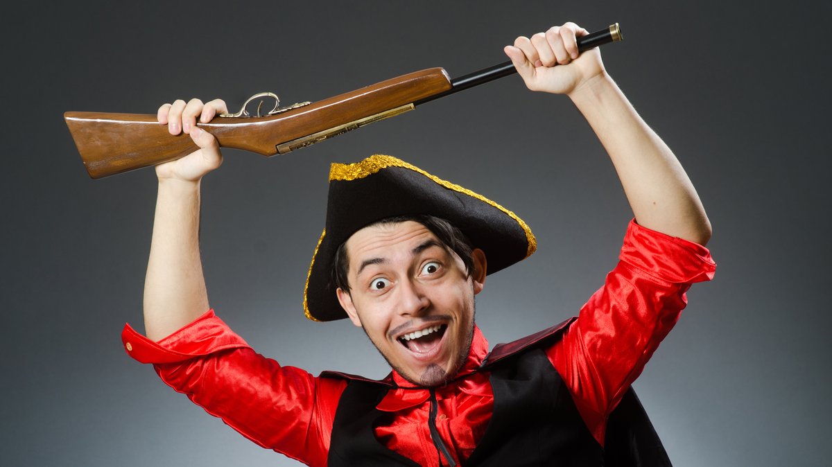 Ein als Pirat verkleideter Mann hält ein Spielzeuggewehr über seinen Kopf.