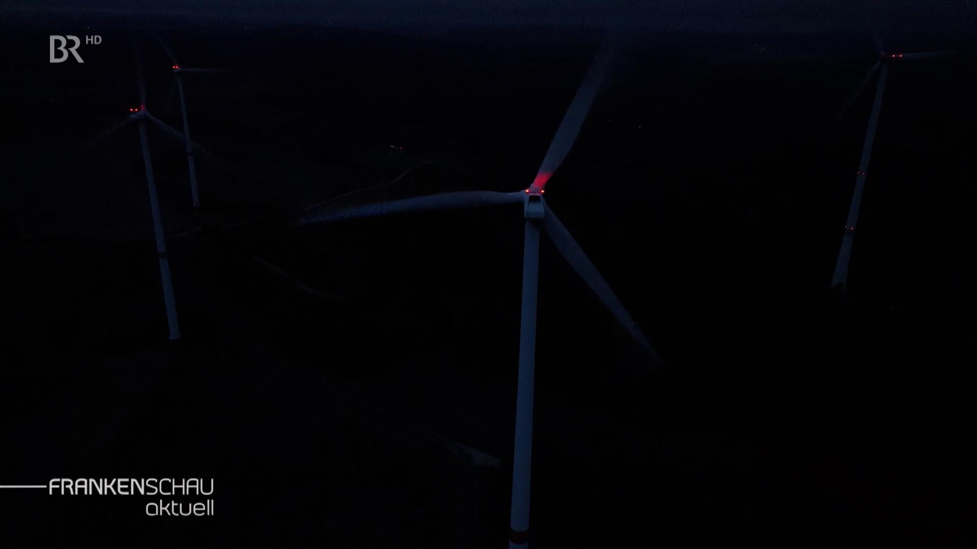 Beleuchtetes Windrad in der Nacht.