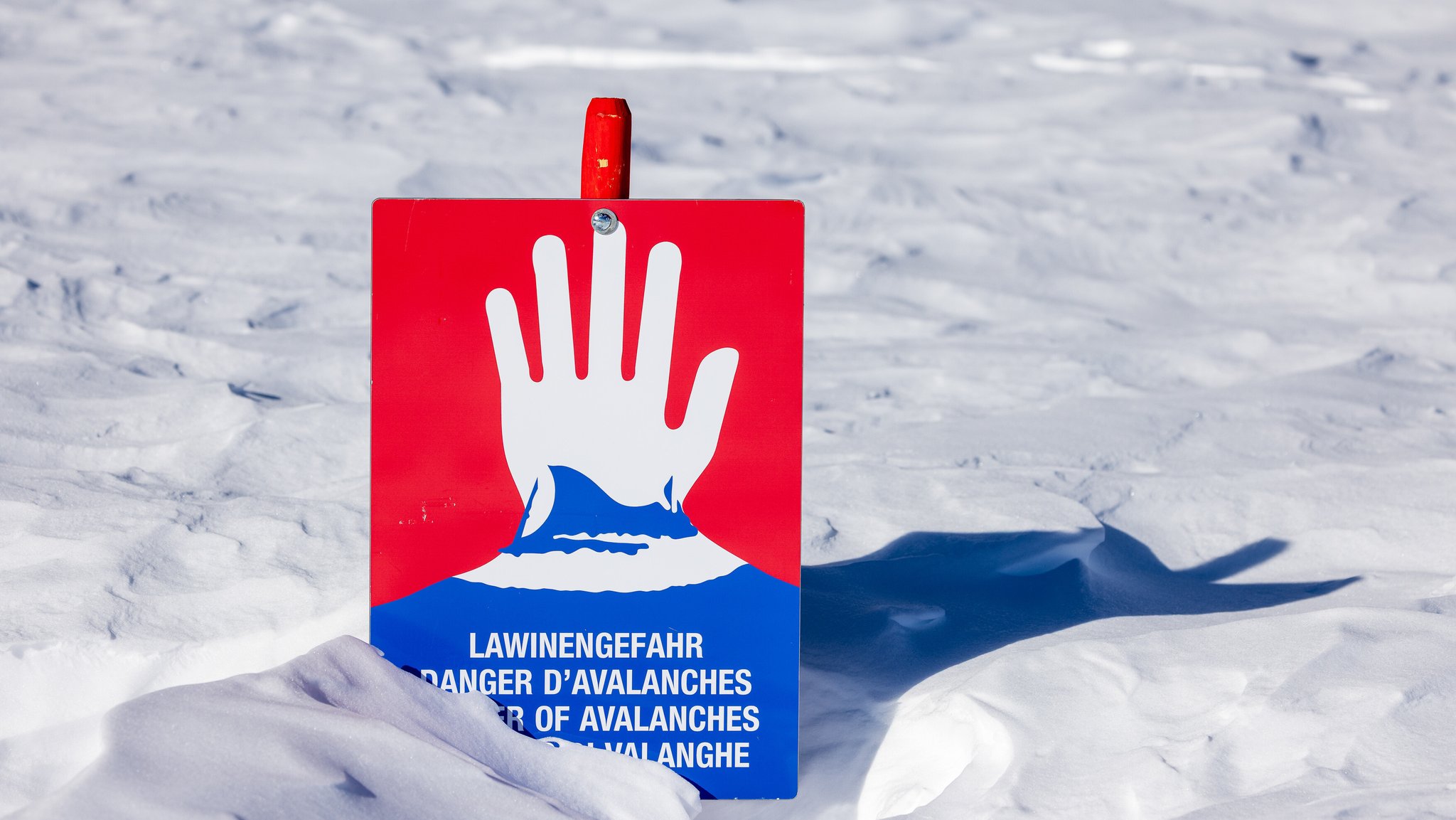 Symbolbild: Ein Schild im Schnee warnt vor Lawinengefahr.