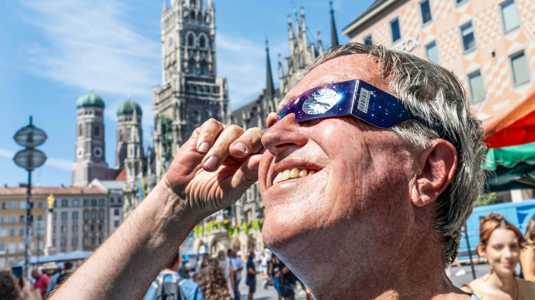 Mit einer Schutzbrille schaut ein Mann auf dem Marienplatz in die Sonne. | Bild: picture alliance / Wolfgang Maria Weber | R7172 Mit einer Schutzbrille schaut ein Mann auf dem Marienplatz in die Sonne.