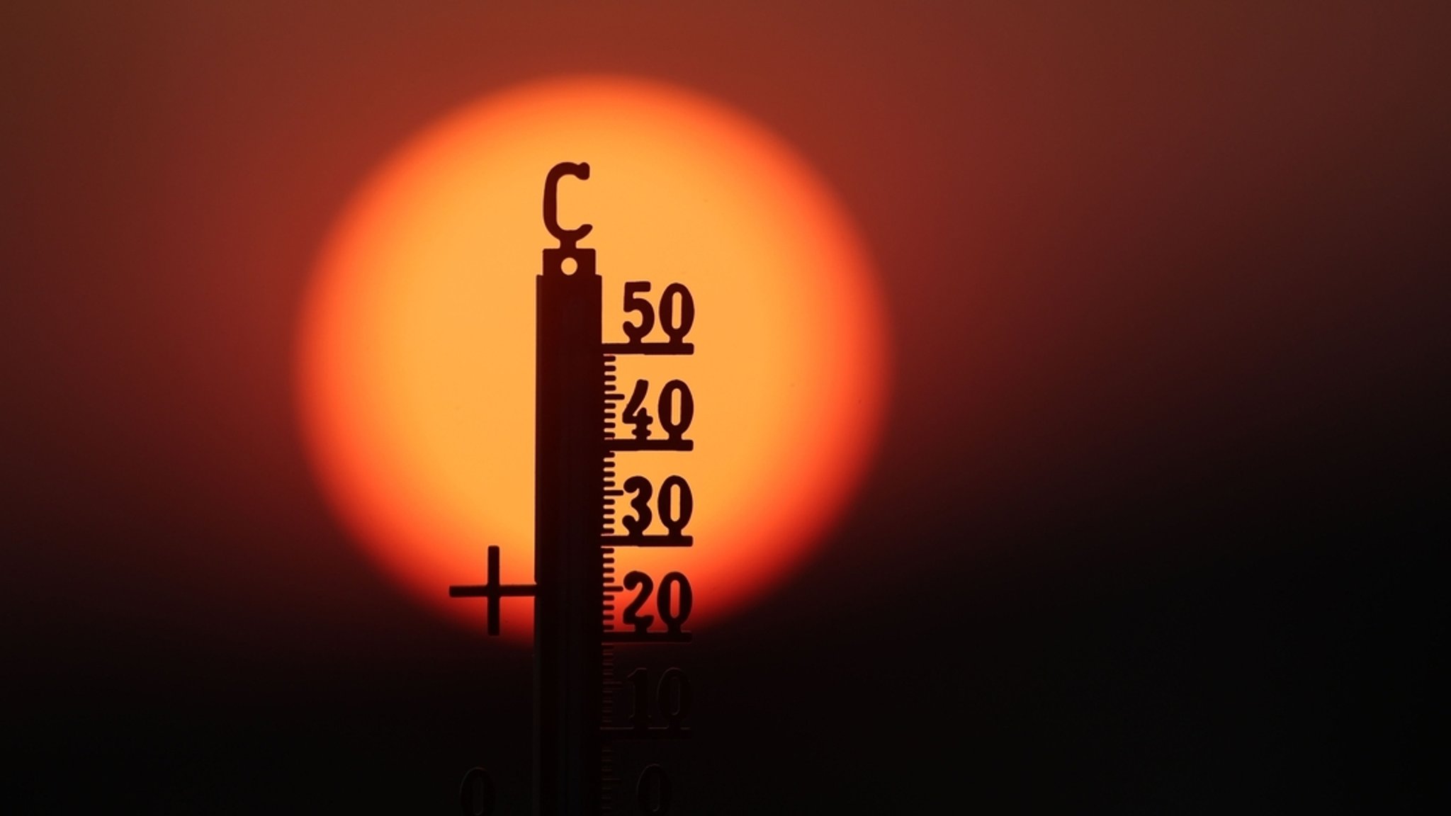 Hinter einem Thermometer geht am Morgen die Sonne auf. | Bild: dpa-Bildfunk/Thomas Warnack Hinter einem Thermometer geht am Morgen die Sonne auf.
