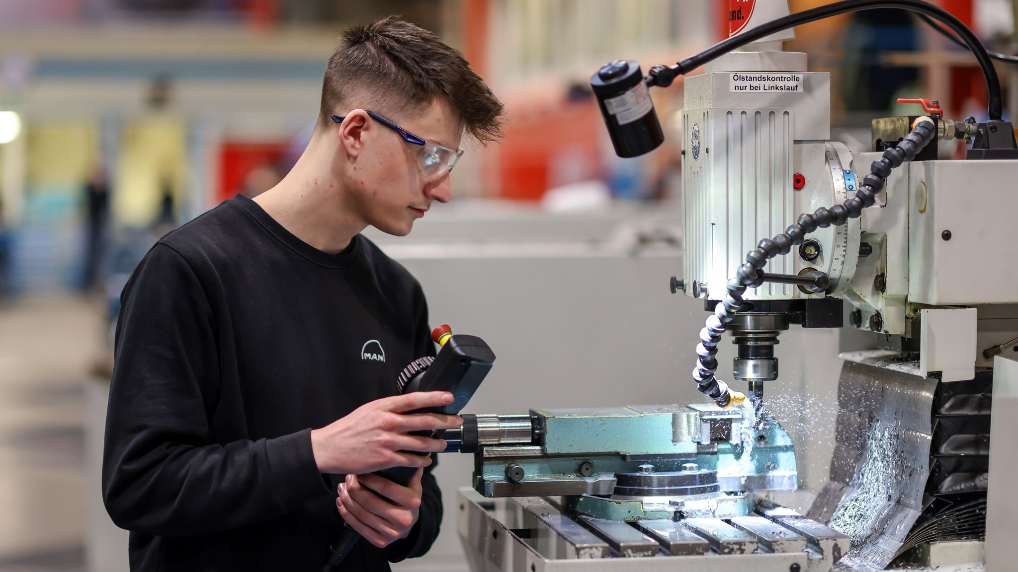 Ein Auszubildender arbeitet an einer Maschine in der Halle von MAN Energy Solutions. | Bild: picture alliance / Rupert Oberhäuser Ein Auszubildender arbeitet an einer Maschine in der Halle von MAN Energy Solutions.
