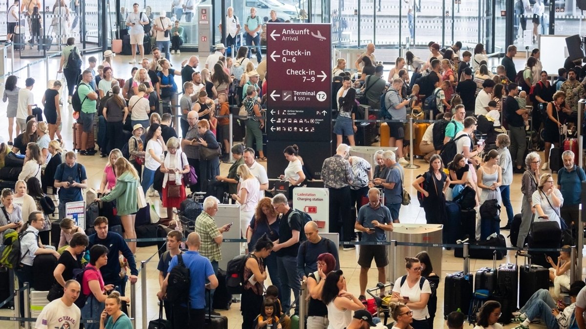 Passagiere warten am Hauptstadtflughafen BER vor Check-in-Schaltern. 
