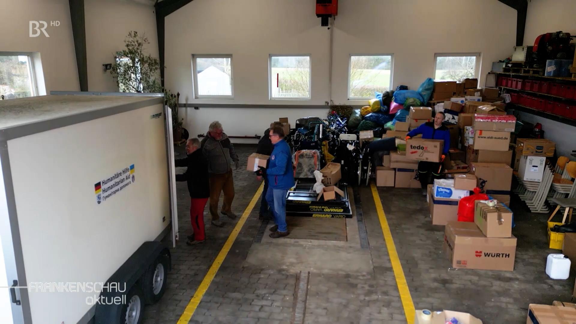 In einer Halle werden Hilfsgüter in einen Transporter geladen.