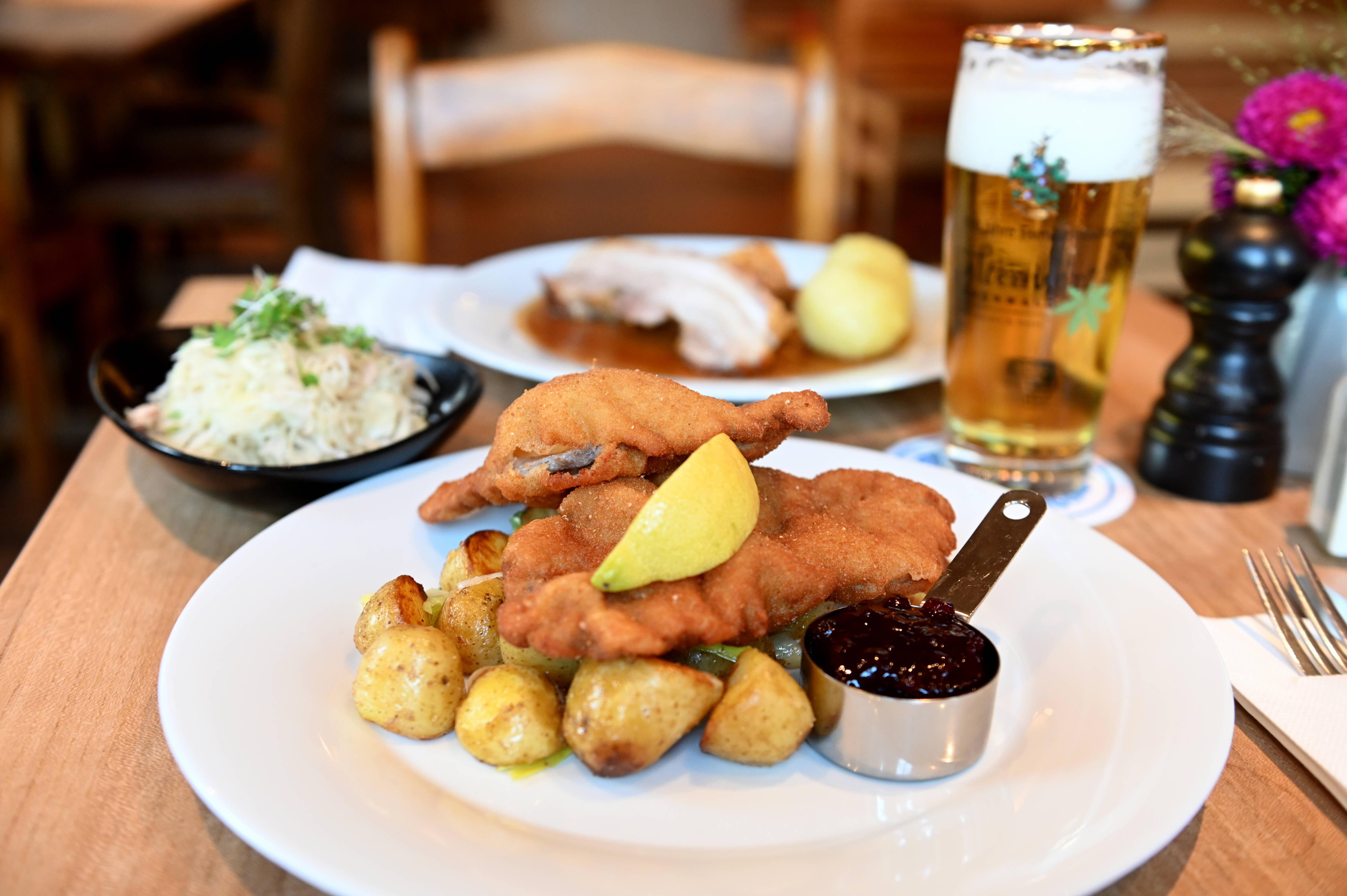 Auf einem Teller liegt ein Schnitzel mit Kartoffeln und Preiselbeermarmelade.