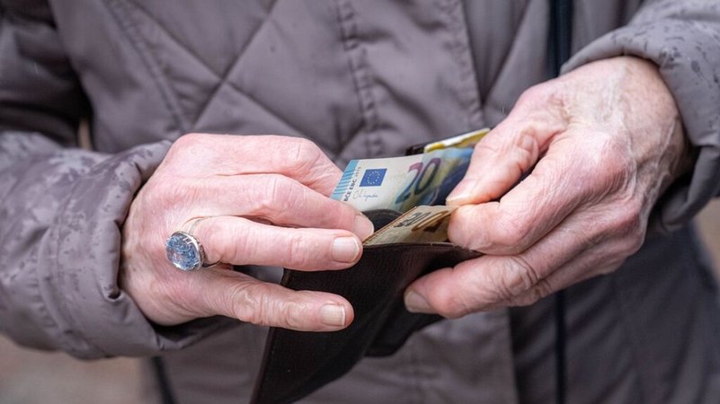 Die Hände einer älteren Person halten eine geöffnete Geldbörse, aus der ein 20-Euro-Schein hervorragt. | Bild: dpa-Bildfunk/Sina Schuldt Die Hände einer älteren Person halten eine geöffnete Geldbörse, aus der ein 20-Euro-Schein hervorragt.