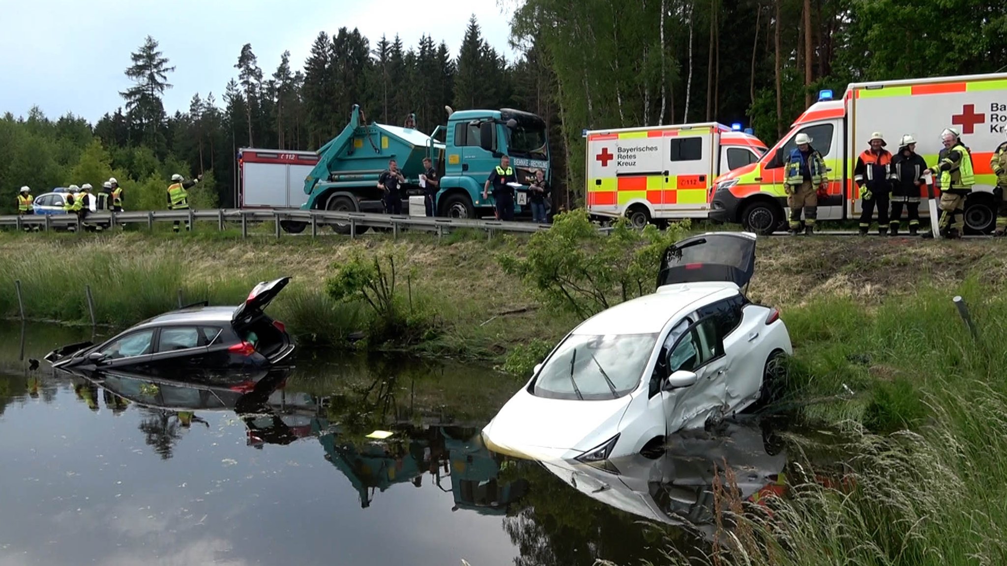 Zwei zerstörte Autos liegen im Wasser.