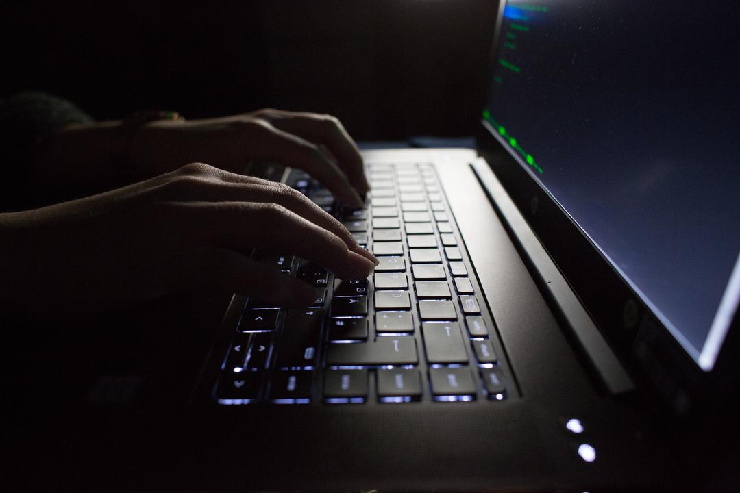 Hände tippen auf einem Laptop mit Porgrammcode auf dem Display.