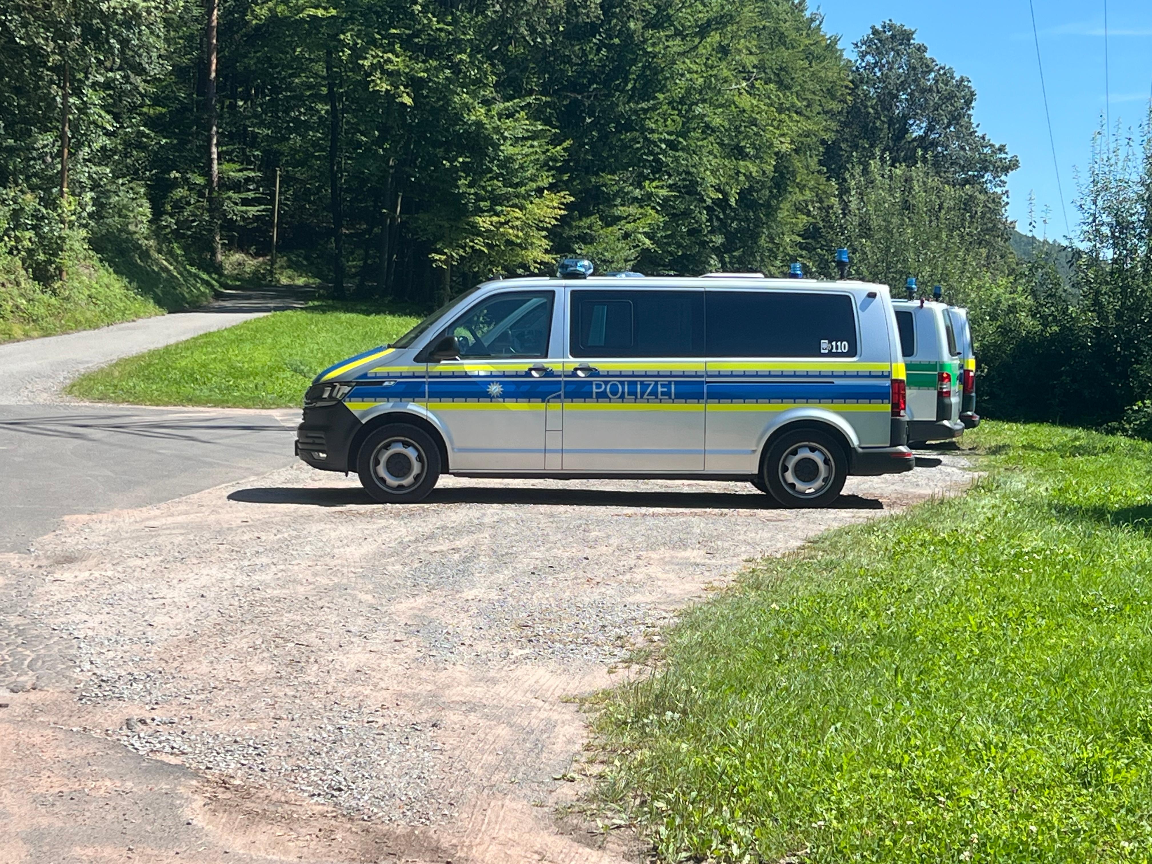 Polizeifahrzeuge auf einem Schotterparkplatz nahe eines Waldes